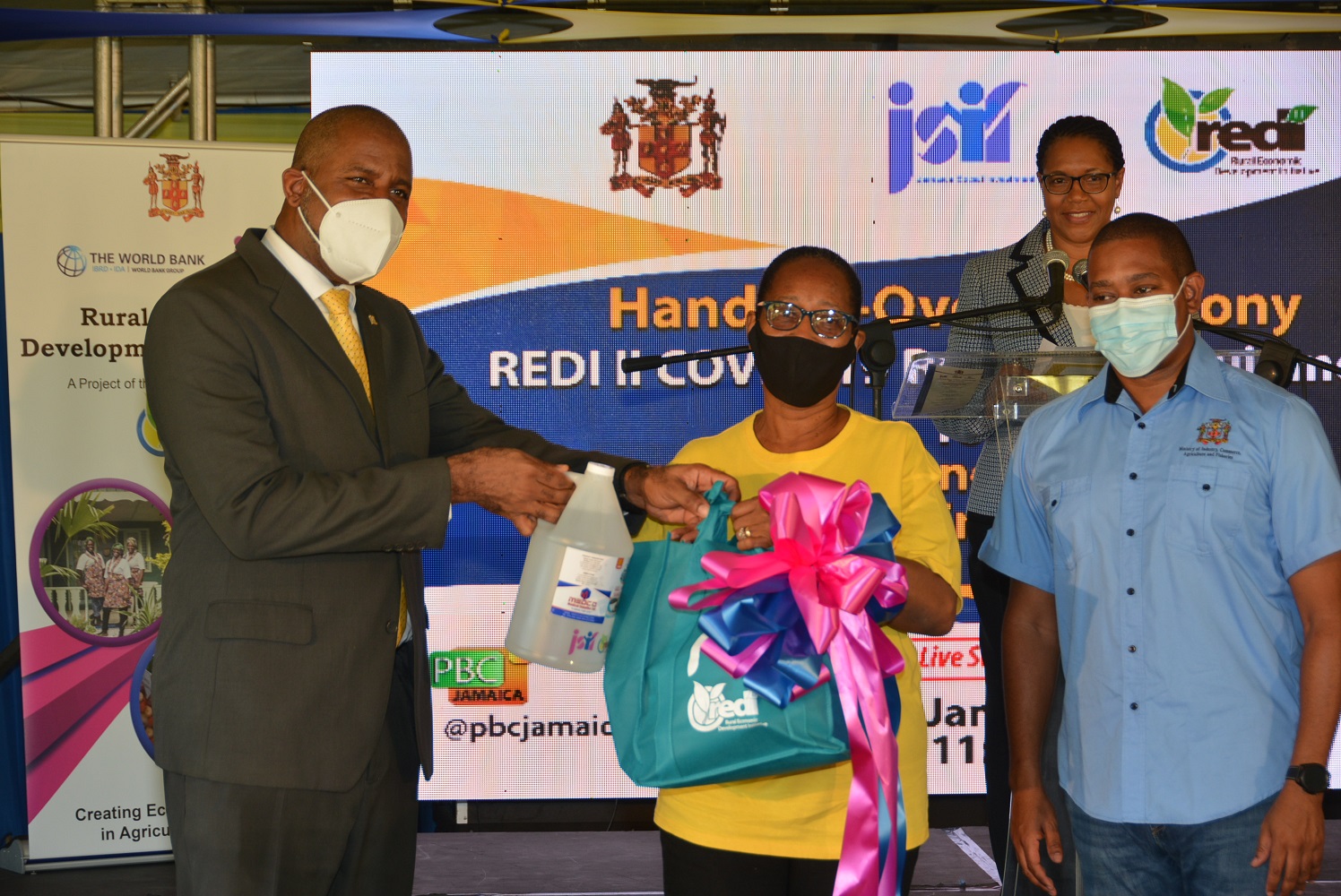 Minister of Agriculture and Fisheries, Hon. Floyd Green (right), looks on as Chairman of the Jamaica Social Investment Fund (JSIF), Dr. Wayne Henry (left), makes a presentation to farmer from Orange Park in St. Ann, Carol Jones-Robinson. Occasion was a ceremony for the handover of coronavirus (COVID-19) resilient supplies to operators of small agriculture and tourism enterprises in St. Ann and Trelawny, on Thursday (January 28), at Grizzly’s Plantation Cove at Richmond Estate in St. Ann.

 