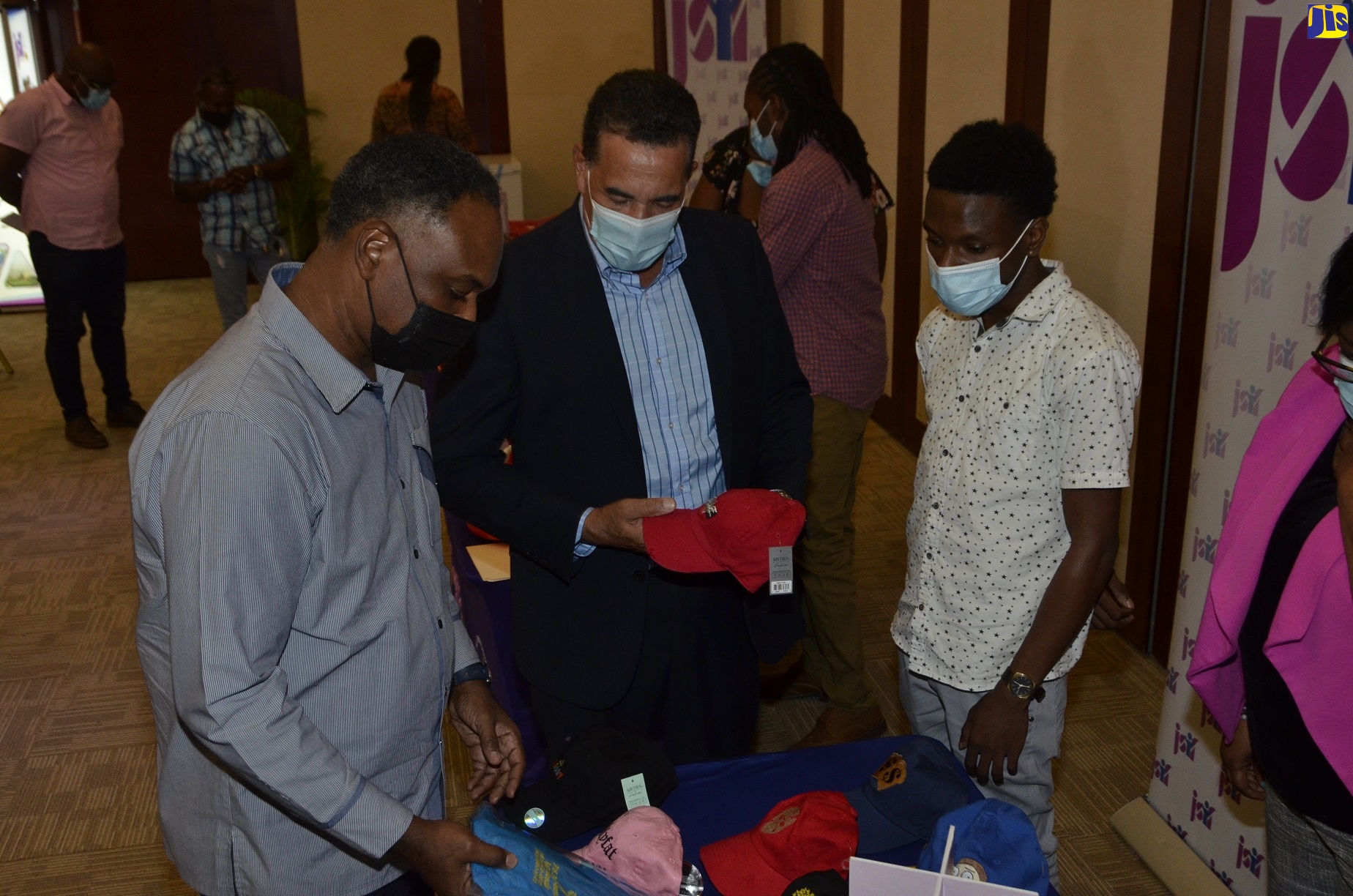 Minister of State in the Ministry of Local Government and Rural Development, Hon. Homer Davis (left), and Managing Director of the Jamaica Social Investment Fund (JSIF), Omar Sweeney (right), inspect the embroidery work of Anchovy, St. James, small business operator, Josh Gooden, at a handover ceremony, held at the Montego Bay Convention Centre in Rose Hall, St. James, on January 21.

