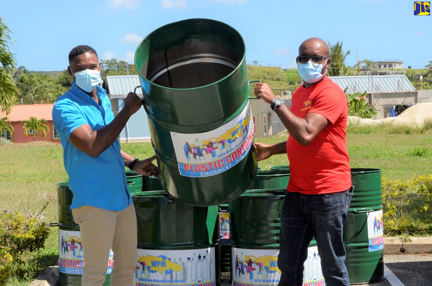 Deputy Mayor of Montego Bay, Councillor Richard Vernon (left), along with Regional Operations Manager, Western Parks and Market (WPM) Waste Management Limited, Garnet Edmondson show off one of 12 drums, placed in the Meadows of Irwin Community in St. James, as part of a pilot plastic bottle separation project launched in the community on Friday (February 12).