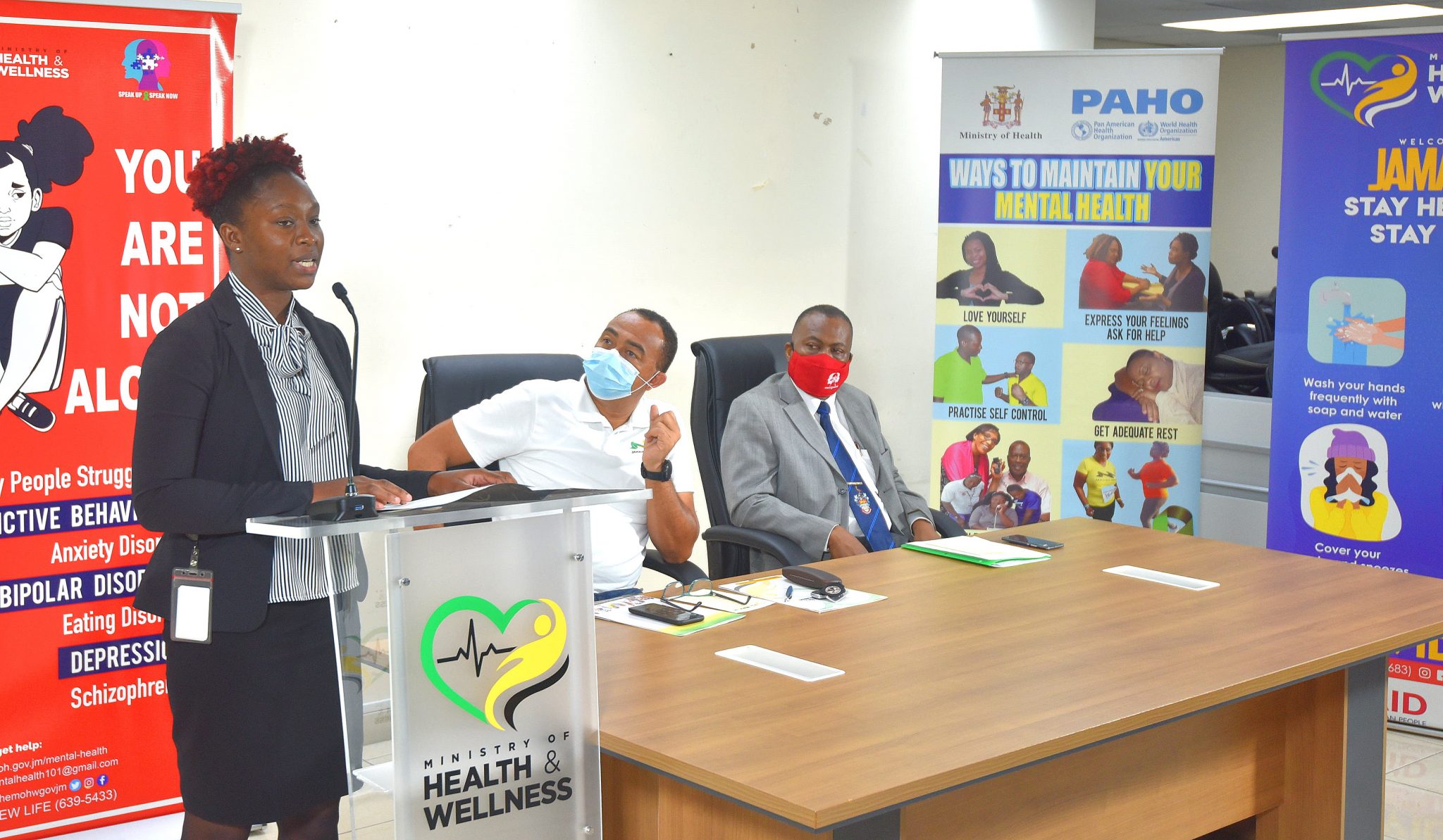 Minister of Health and Wellness, Dr. the Hon. Christopher Tufton (centre), listens as volunteer in the Mental Health Response Programme, Shavina Lennon (left), addresses the recent graduation ceremony. Also listening is Director of Mental Health and Substance Abuse in the Ministry, Dr.  Kevin Gouldbourne.
