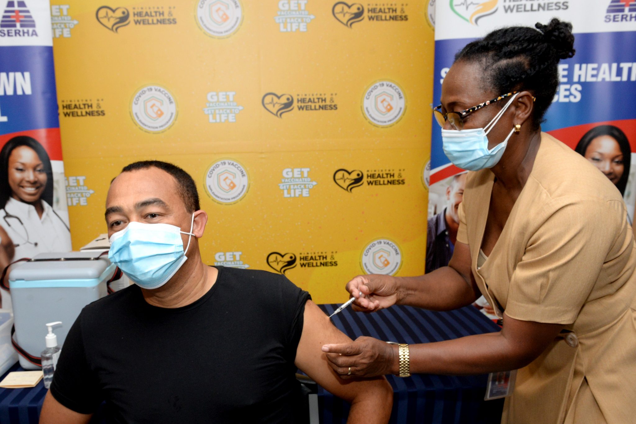 Minister of Health and Wellness, Dr. the Hon. Christopher Tufton (left), receives the COVID-19 vaccine, which was administered by Public Health Nurse, Teldra Burrell-Lewis, at the Spanish Town Hospital on March 19.