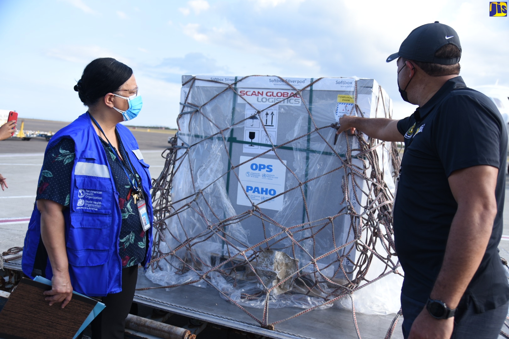 Minister of Health and Wellness, Dr. the Hon. Christopher Tufton (right), examines a shipment of AstraZeneca vaccine from the COVAX Facility, which arrived at the Norman Manley International Airport on Monday (April 26). Sharing the moment (at left) is PAHO/WHO Country Representative for Jamaica, Bermuda and the Cayman Islands, Bernadette Theodore Gandi.