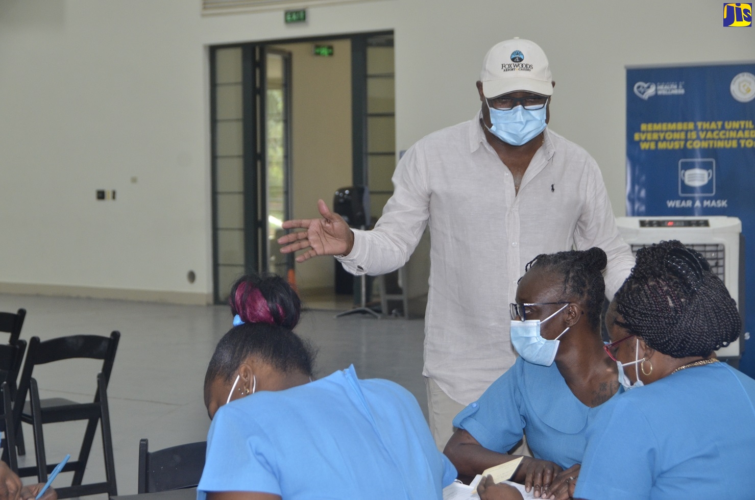 Tourism Minister, Hon. Edmund Bartlett (standing right) engages with Community Health Aides during a coronavirus (COVID-19) vaccination blitz at the Montego Bay Convention Centre in St. James on Saturday (April 10).