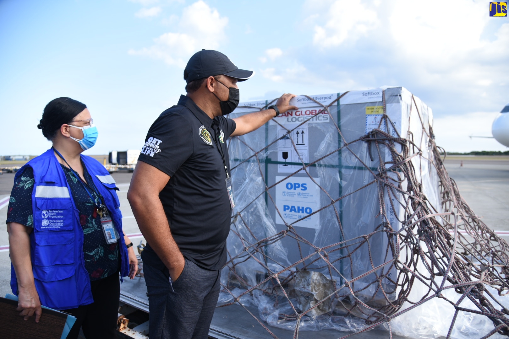 Minister of Health and Wellness, Dr. the Hon. Christopher Tufton (right), reads the label on a shipment with the AstraZeneca vaccine, which arrived at the Norman Manley International Airport in Kingston, on Monday (April 26). With the Minister is the PAHO/WHO Country Representative for Jamaica, Bermuda and the Cayman Islands, Bernadette Theodore Gandi.