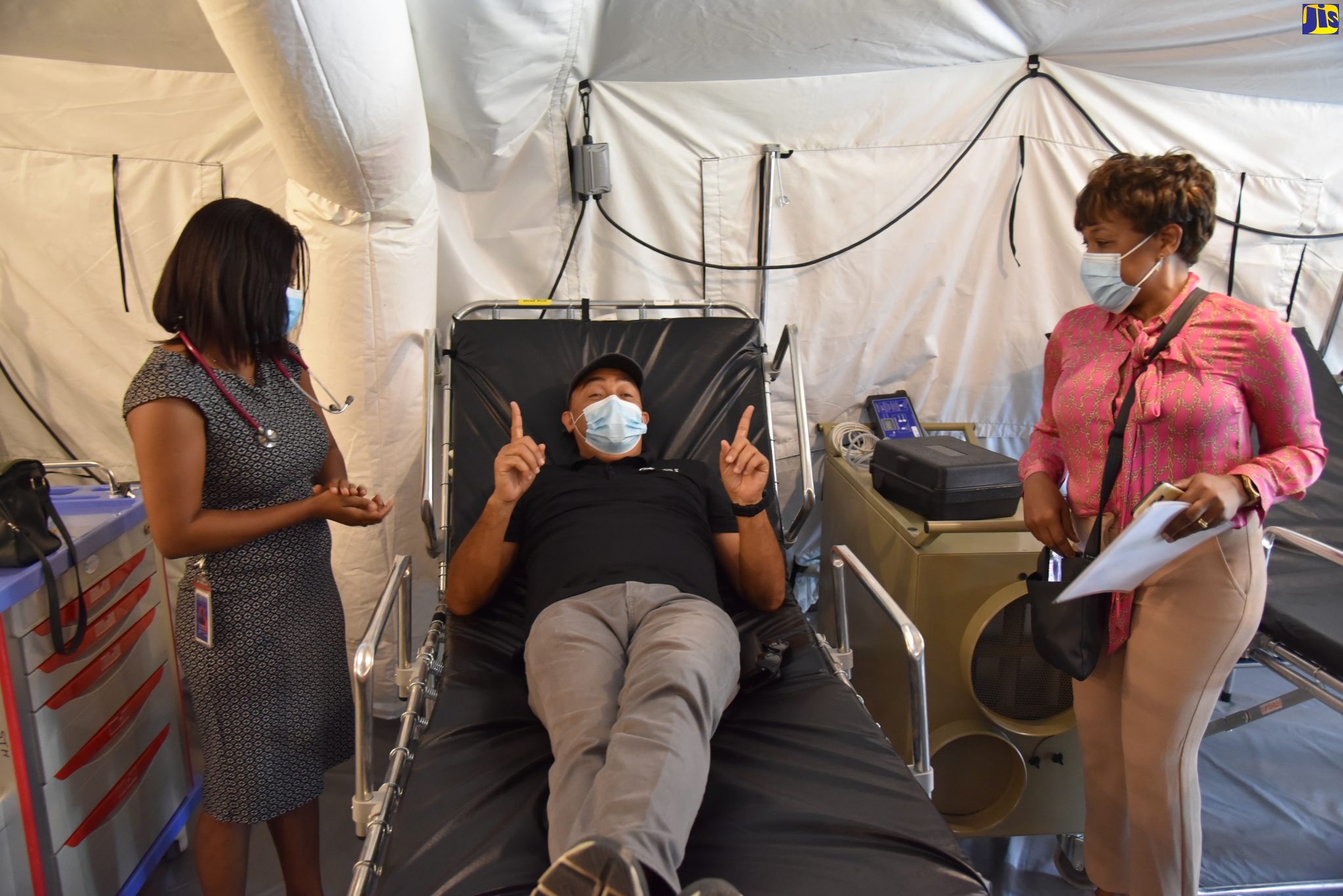 Minister of Health and Wellness, Dr. the Hon. Christopher Tufton (centre), tries out one of the beds in the field hospital at the Spanish Town Hospital, which was officially opened to patients on Friday (April 9). Looking on are Chief Medical Officer, Spanish Town Hospital, Dr. Jacqueline James (right), and Medical Doctor, Dr. Aneita Beckford.