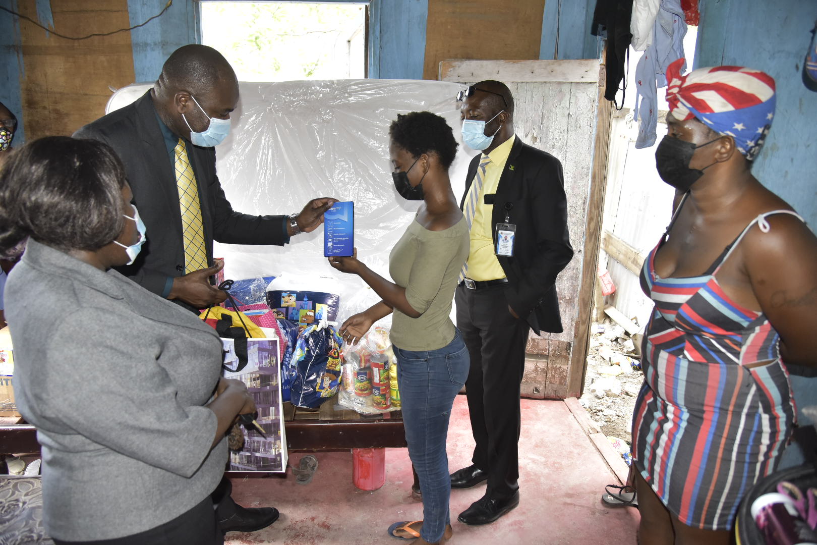 State Minister, Ministry of Labour and Social Security, Hon. Zavia Mayne (second left), presents Queen’s High school student, Shanequa Smart (centre), with a tablet to support her online learning. Looking on (from left) are Director for the Ministry’s Early Stimulation Programme (ESP), Antonica Gunter-Gayle; Director, Public Relations and Communications in the Ministry, Vando Palmer and Shanequa's mother, Kadian Harrison. During a visit to the family home in St. Andrew on May 25, the Ministry team also handed over food items, school supplies, a new mattress and disposable underwear. The  Ministry, as part of actvities to mark Child Month, has been making presentations to families of children enrolled at the ESP, based on their needs. Ms. Harrison has a child with Down Syndrome at the ESP. 

