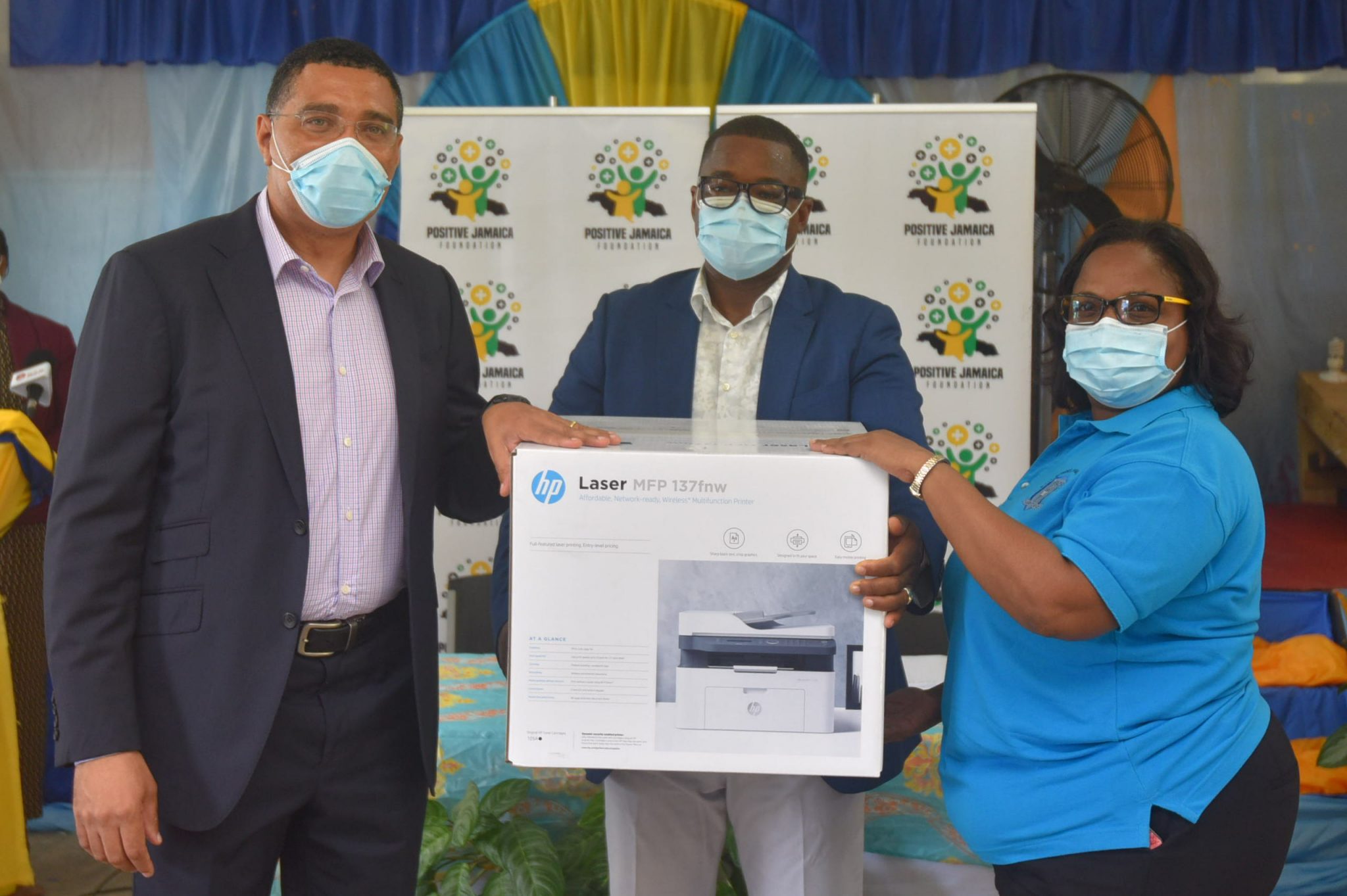 Prime Minister, the Most Hon. Andrew Holness (left), presents a printer to Principal of the the Salt Spring Primary and Infant School, Norma Brydson (right), while Member of Parliament for Central St. James, Heroy Clarke, shares in the moment.  Occasion was a ceremony at the school on Friday (May 21) for the handover of 30 tablets and a laser printer, which were donated through the Prime Minister