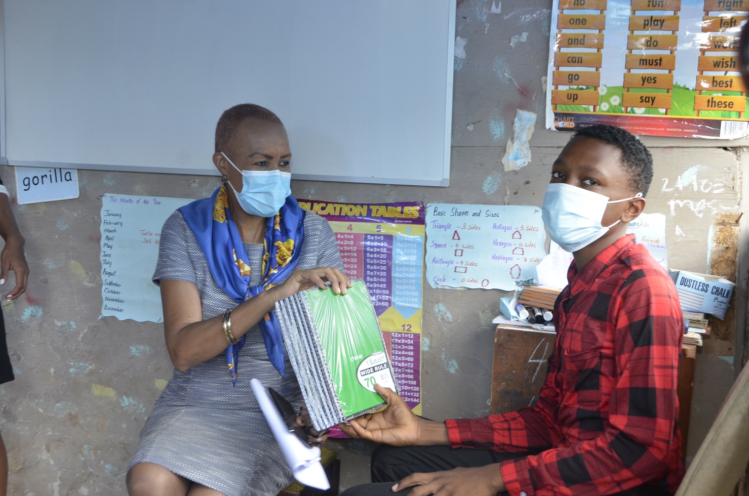 Minister of Education, Youth and Information, Hon Fayval Williams (left), presents notebooks to 14-year-old Ferncourt High student of Queenhythe, Discovery Bay, St. Ann, Kelvin Peart, to assist with his tutoring efforts in the community. The Minister, along with a team from the Ministry’s Region Three office visited the teenager in his community on Thursday, June 3. ,