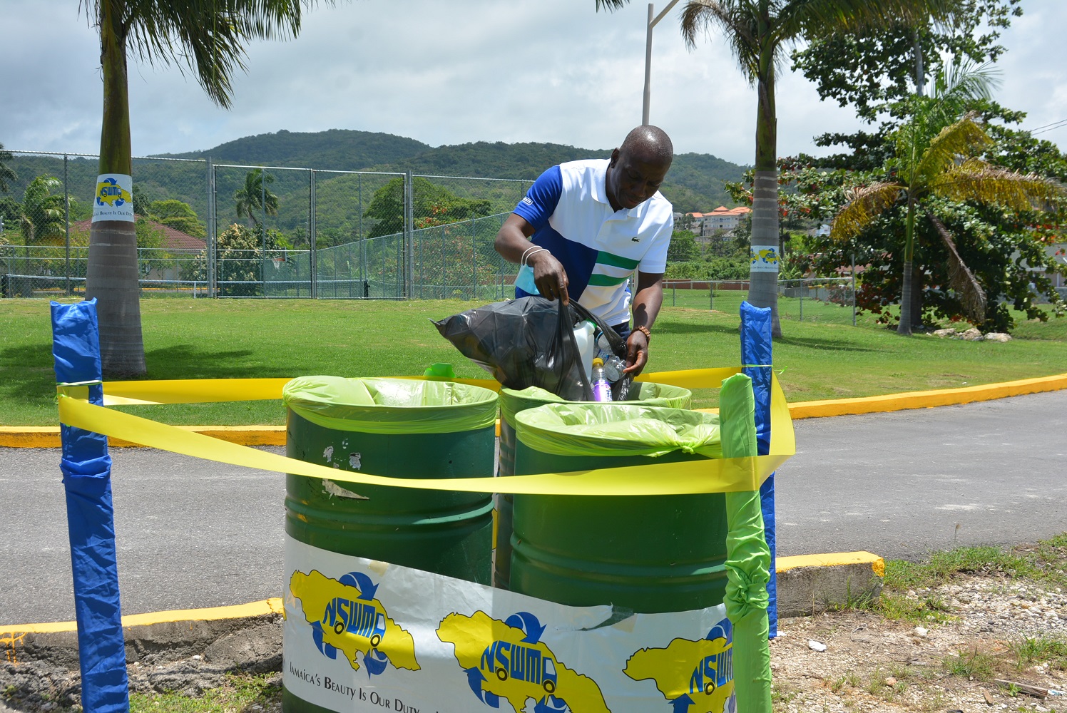 Executive Director for the National Solid Waste Management Authority (NSWMA), Audley Gordon, disposes plastic bottles into a receptacle for recycling during a recent ceremony for the commissioning into service of three plastic disposal bins at Drax Hall Manor in St. Ann. 