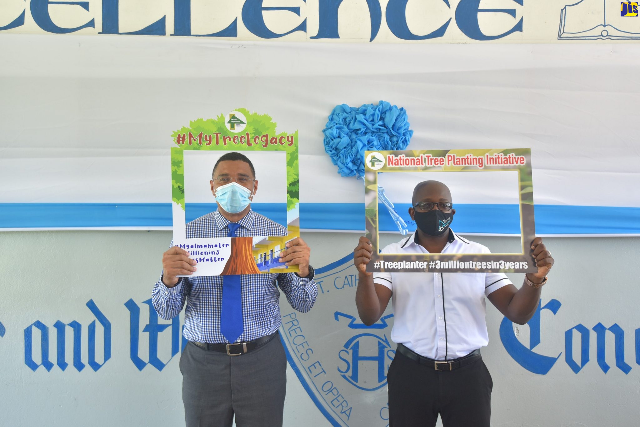 Prime Minister, the Most Hon. Andrew Holness (left); and Minister of Housing, Urban Renewal, Environment and Climate Change, Hon. Pearnel Charles Jr., display signs to show their commitment towards planting trees, during the #MyTreeLegacy Tree Planting Ceremony, held at St. Catherine High School on Friday (June 18).