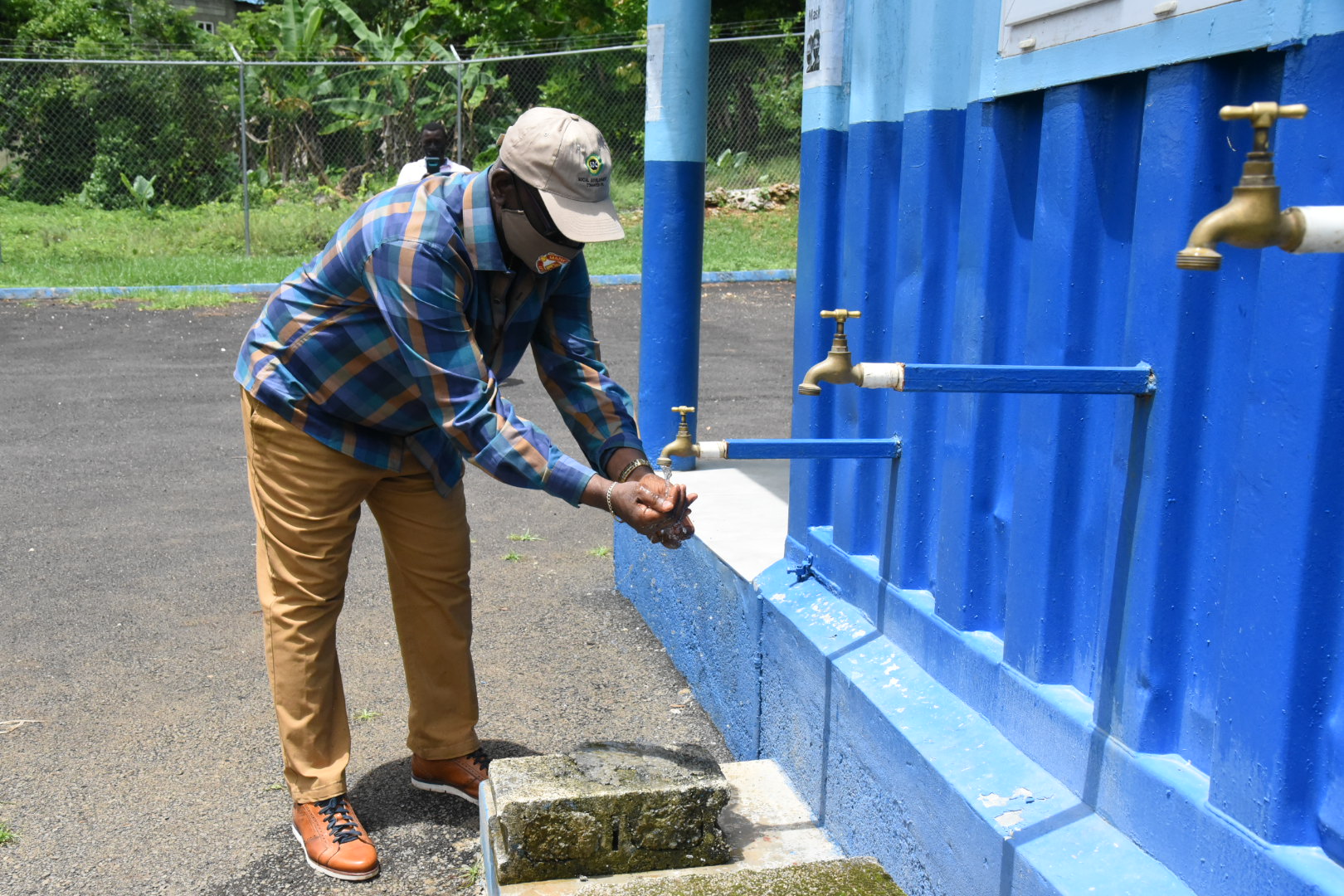 Minister of Local Government and Rural Development, Hon. Desmond McKenzie, uses the tap at the first water shop built in Commodore, during a tour of the Portland community on Friday (June 11).