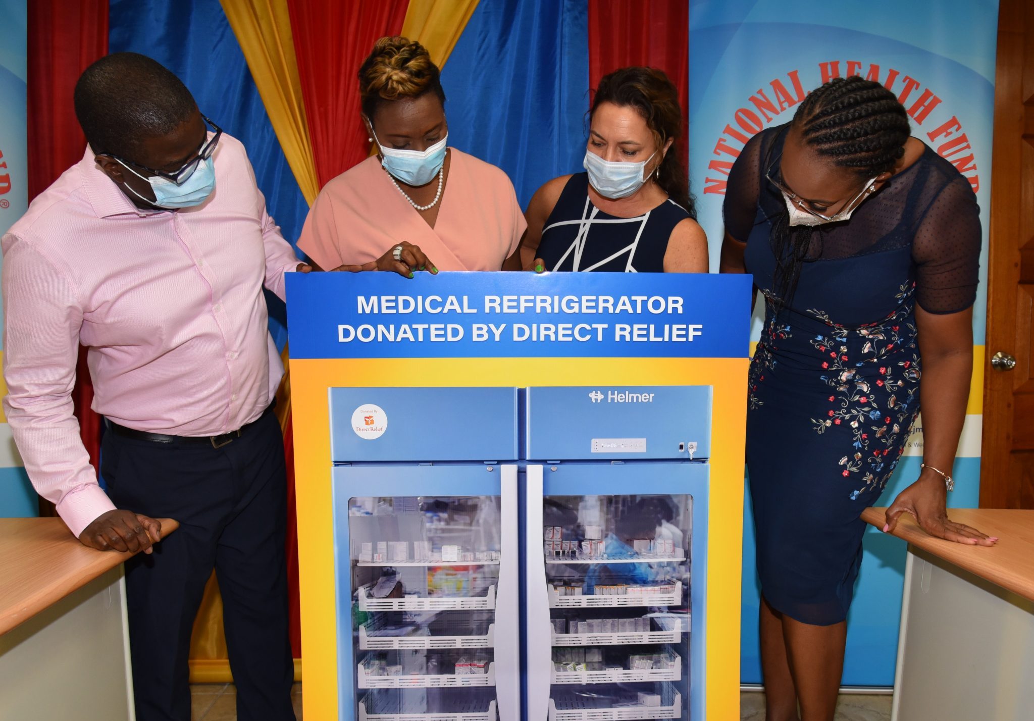 State Minister for Health and Wellness, Hon. Juliet Cuthbert-Flynn (second left), looks at a picture of one of the 20 medical refrigeration units donated to the public health system by international humanitarian aid organisation Direct Relief. The units were officially handed over during a ceremony at the National Health Fund (NHF), Dominica Drive, St. Andrew, on Thursday (July 8). Also looking on (from left) are NHF Chief Executive Officer,  Everton Anderson; Director of Programme Operations, Direct Relief, Genevieve Bitter; and Member of Parliament for East Rural St. Andrew, the Most Hon. Juliet Holness.