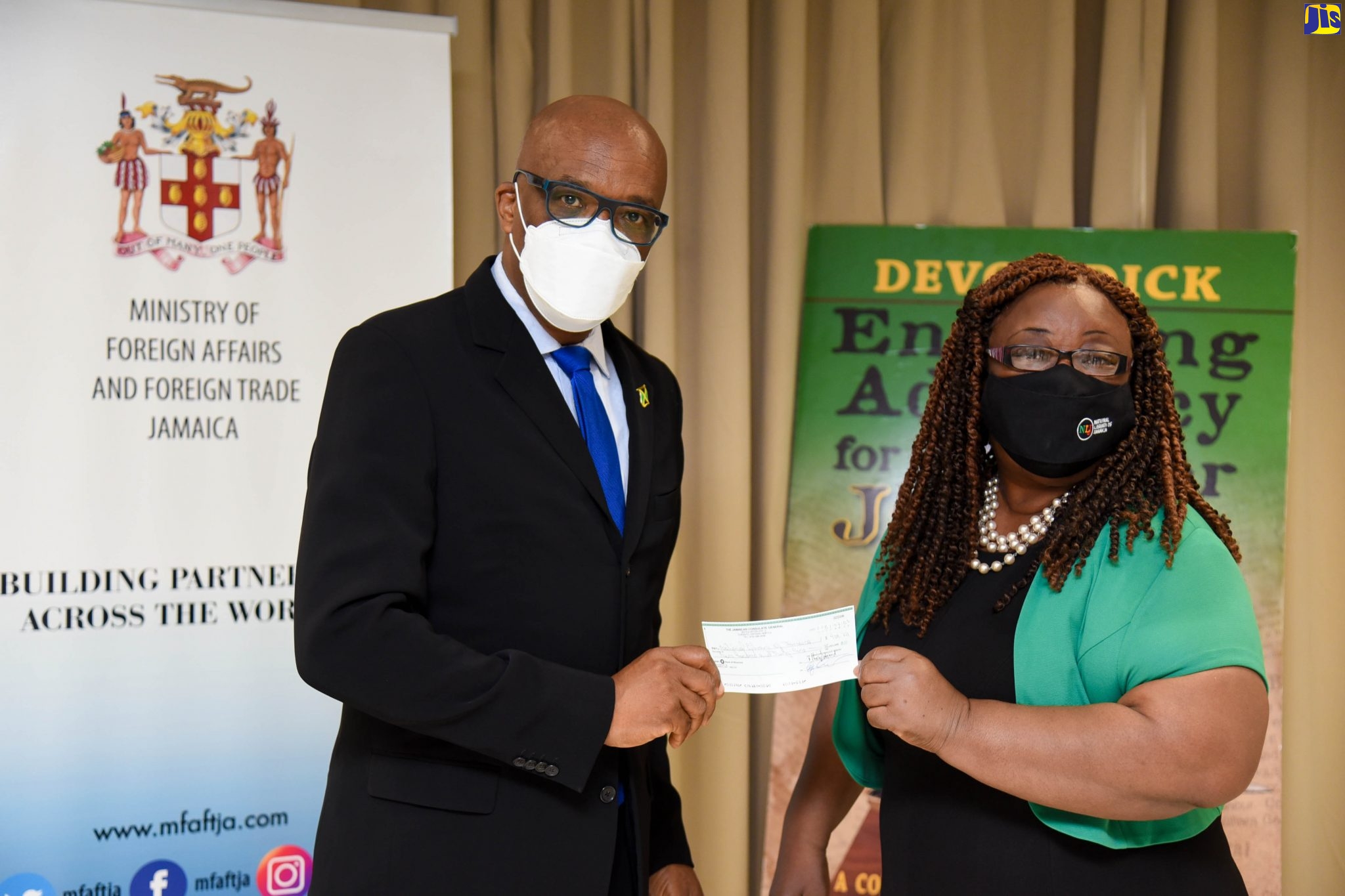 State Minister in the Ministry of Foreign Affairs and Foreign Trade, Senator the Hon. Leslie Campbell (left), hands over a cheque for Can$939.72 (approximately J$117,000) to National Librarian, Beverley Lashley, at the Ministry in downtown Kingston on Thursday (August 12). The donation is on behalf of the Consulate General of Jamaica in Toronto, Canada.