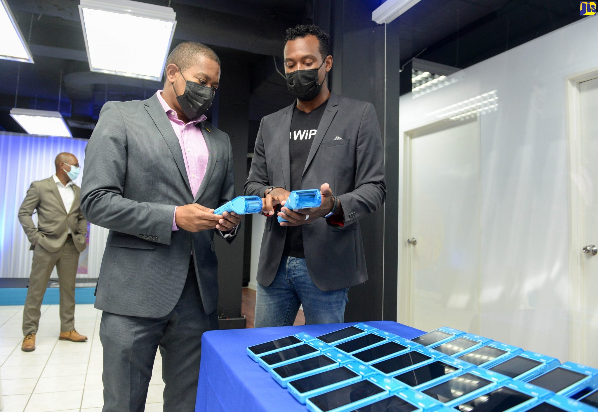 Minister of Agriculture and Fisheries, Hon. Floyd Green (left), speaking with WiPay’s Country Manager for Jamaica, Kibwe McGann, about the point-of-sale terminals that the organisation provides, during the opening ceremony for the entity’s WiPay’s headquarters in New Kingston on Thursday (August 26).