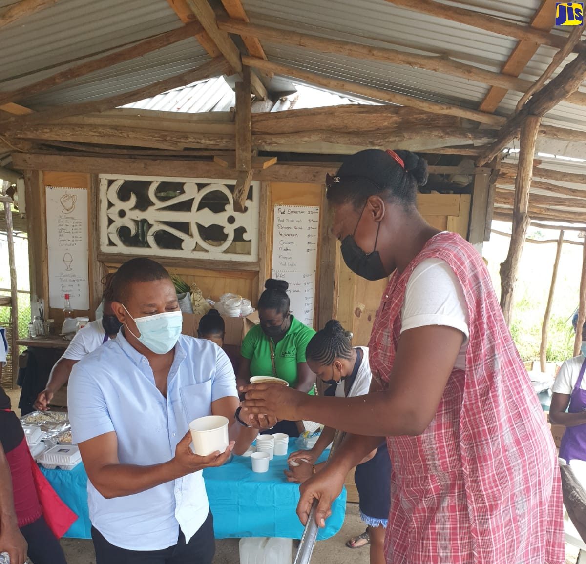 Minister of Agriculture and Fisheries and Member of Parliament for Southwest St. Elizabeth, Hon. Floyd Green, assists in packaging meals for delivery to elderly persons and shut-ins in Middle Quarters recently, under an initiative organised by the Middle Quarters Community Development Committee (CDC). Serving the soup is Secretary of the CDC, Natasha Williams.