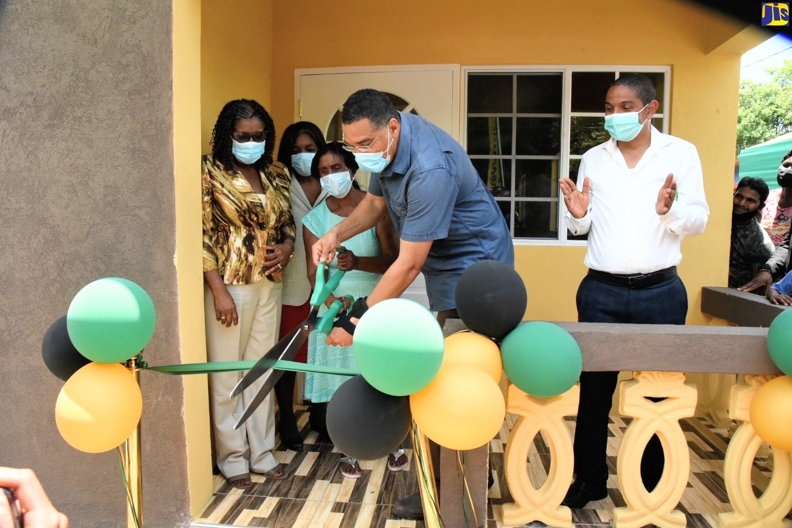 Prime Minister, the Most Hon. Andrew Holness  (second right), cuts the ribbon to officially hand over a three-bedroom house to a family in his West Central St. Andrew, recently. Others pictured (from left)) are Permanent Secretary in the Office of the Prime Minister, Audrey Sewell, family members for the unit, and Mayor of Kingston, Senator Delroy Williams.