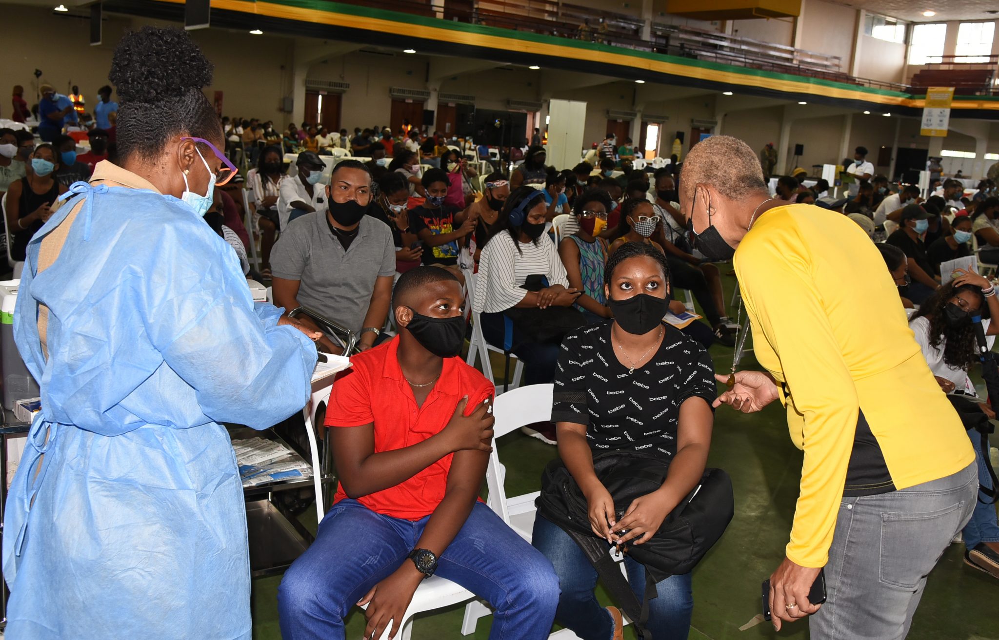 Minister of Education, Youth and Information, Hon. Fayval Williams (right ), in conversation with Jade Monique Davis (2nd right) and Adam Davis (2nd left), on day one of the four-day children’s coronavirus (COVID-19) vaccination blitz at the National Arena, on Saturday (August 21). At left is nurse, Patricia Coates. (Rudranath Fraser photo)

