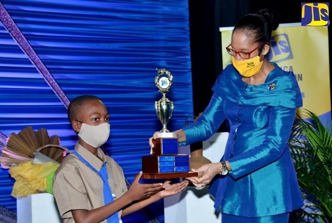 Chief Executive Officer of the Jamaica Information Service (JIS), Donna-Marie Rowe (right), presents a trophy to student of Morgan’s Pass Primary School in Clarendon, Amani Shrouder, who was the winner of the Essay category in the 2020 JIS Heritage Competition. Photo: Mark Bell