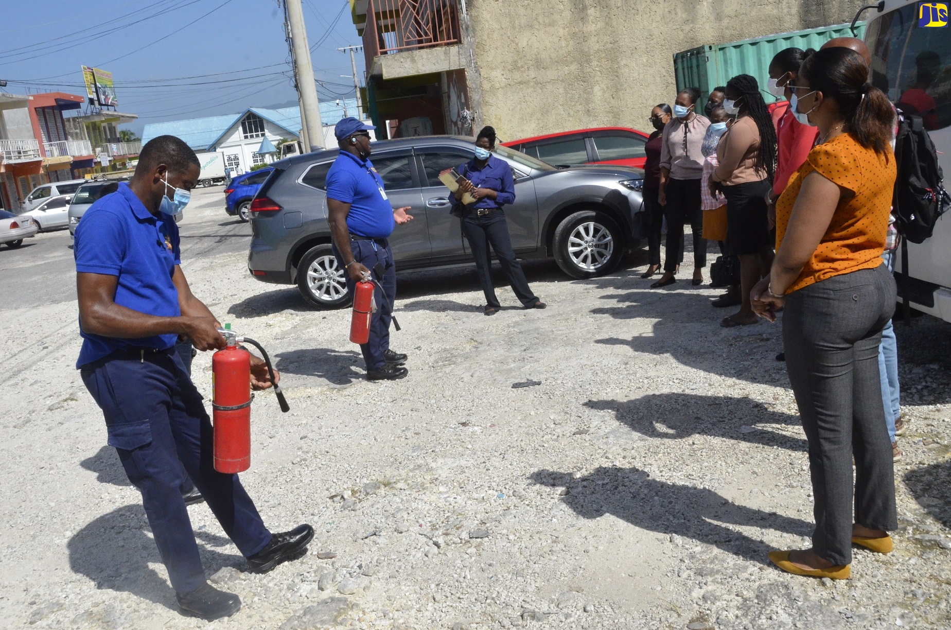 Acting Sergeant assigned to the Jamaica Fire Brigade’s (JFB) Fire Prevention in St Elizabeth, Dwight Campbell (second left), along with Acting District Officer of the JFB in St. Elizabeth, Owen Ranglin (left), instruct staff of the St Elizabeth Probation Office on fire safety tips, during an emergency drill in Santa Cruz on Friday, October 29.