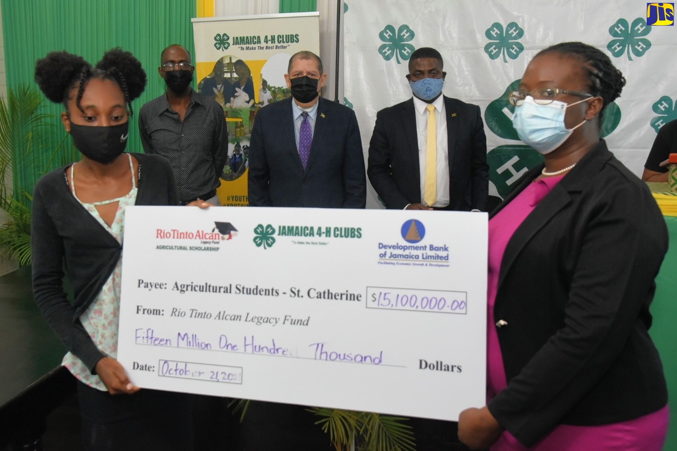 Minister of Industry, Investment and Commerce, Hon. Audley Shaw (centre), who also has responsibility for Agriculture and Fisheries, observes as Rio Tinto Alcan Legacy Fund Scholarship Steering Committee member, Villet Kelly-Bennett (right), presents a symbolic cheque in the sum of $15.1 million to College of Agriculture, Science and Education (CASE) graduate, Quindora Garrett, who accepted on behalf of students and Jamaica 4-H Club members in St. Catherine applying for scholarships to pursue agricultural studies during the 2021/22 academic year. Others (from second left) are Jamaica 4-H Clubs Executive Director, Dr. Ronald Blake; and Rio Tinto Alcan Legacy Fund Scholarship Steering Committee Chairman and Holmwood Technical High School Principal, Hidran McKulsky. The semi-virtual ceremony was hosted by Jamaica 4-H Clubs in Kingston, today (October 21).