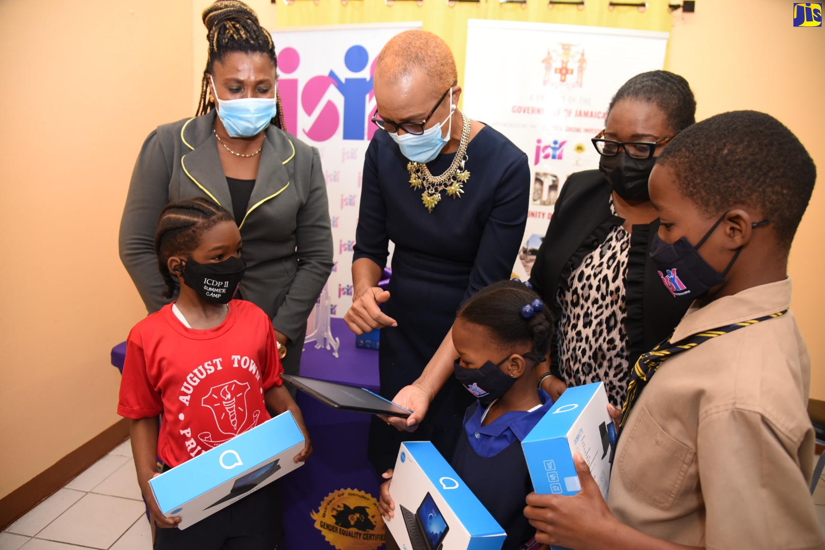Minister of Education, Youth and Information, Hon. Fayval Williams (thir left), points out the features of one of several tablets donated by the Jamaica Social Investment Fund (JSIF)  to students of the August Town Primary School in St. Andrew. The students (from left) are Jequan Treleven, Janoie Allen and Francois Bersick. Looking on are Social Development Manager at JSIF, Mona Sue-Ho (second right) and August Town Primary School Principal, Jennifer Solomon. The handover ceremony was held at the school on Thursday (November 11).
