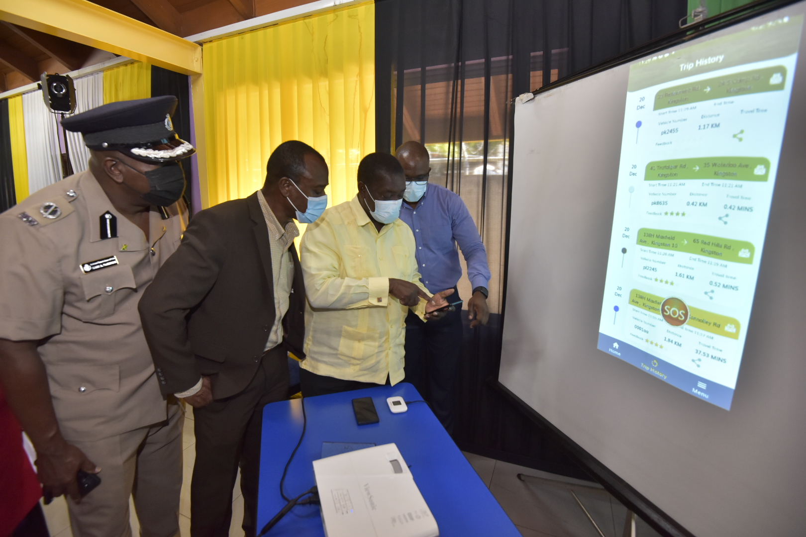Transport and Mining Minister, Hon. Robert Montague (second right) tries out the new Travel Pal application,  during the launch on Monday (December 20) at the Ministry’s Half-Way-Tree offices in Kingston. Looking on (from left) are Head of the Public Safety and Traffic Enforcement Branch (PSTEB), Assistant Commissioner of Police (ACP) Gary McKenzie; Managing Director of the Transport Authority (TA), Willard Hylton; and Information Communication Technology (ICT) Manager, TA, Vernon Walters.