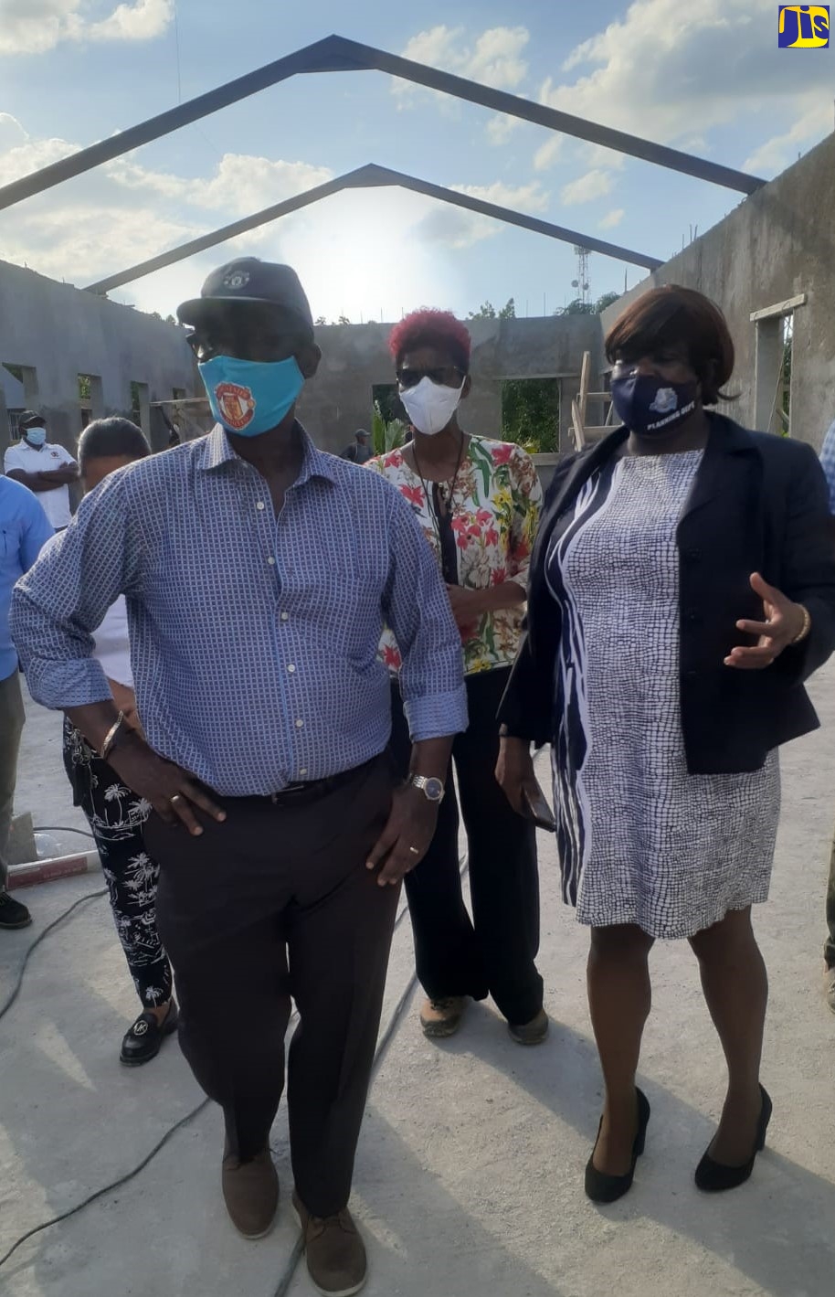 Minister of Local Government and Rural Development , Hon. Desmond McKenzie, (foreground) gets a firsthand view of the progress of work on the new male ward being built at the Westmoreland Infirmary, during a tour of the project site  recently. He is accompanied by Chief Executive Officer at the Westmoreland Municipal Corporation, Marvalyn Pitter (right); and Chief Engineering Officer at the Corporation, Ava Murdock.