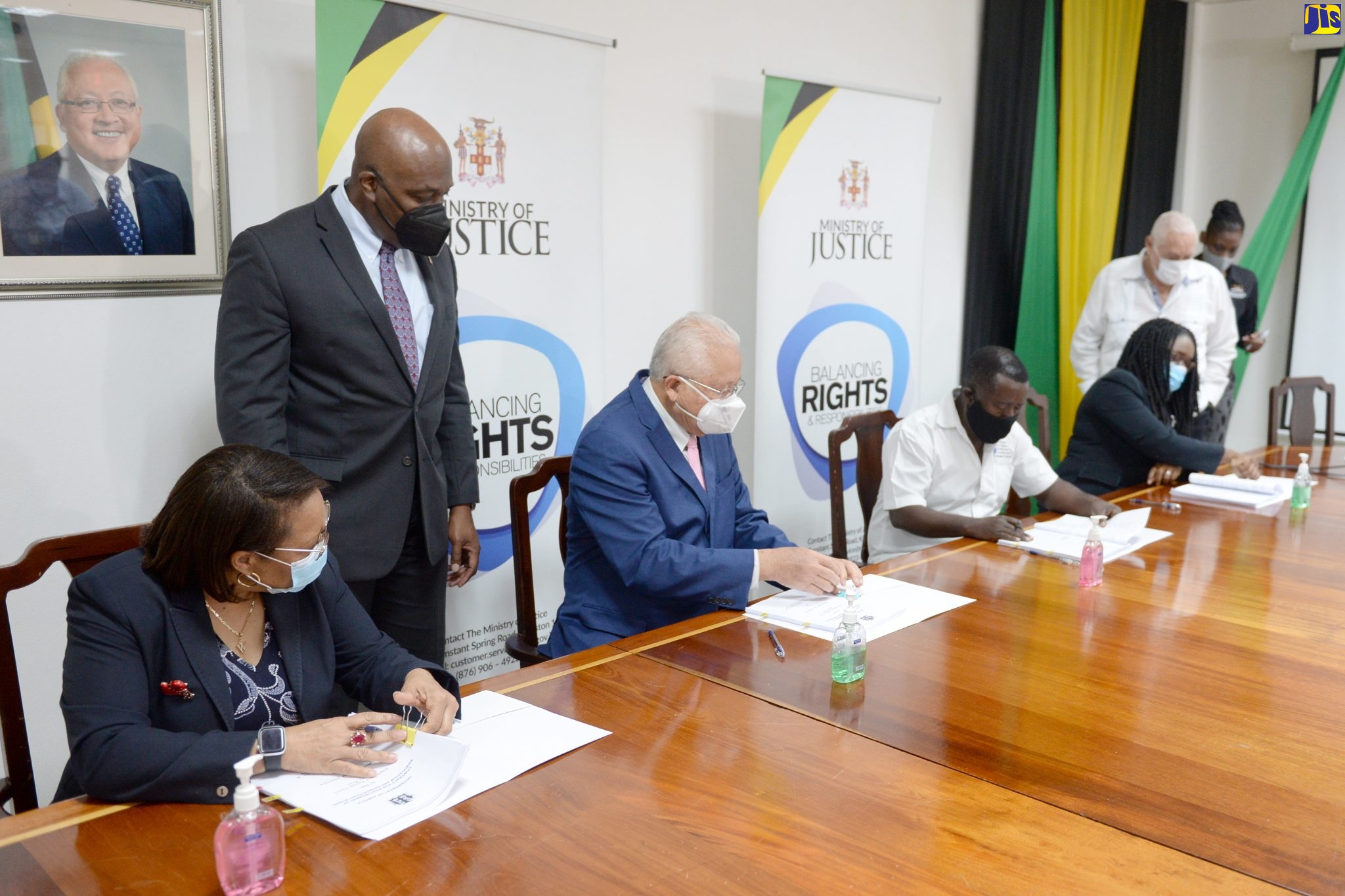 Justice Minister, Hon. Delroy Chuck (seated, second left), signs the contract for the $120 million Clarendon Parish Court renovation project, during a semi-virtual ceremony at the Ministry in St. Andrew on Friday (December 10). Others seated (from left) are: Acting Permanent Secretary in the Justice Ministry, Grace Ann Stewart McFarlane; Managing Director of Greenhouse Consultants and Construction Limited, George Henry; and Director, Court Administration Division (CAD), Tricia Cameron Anglin, who also signed the document. Observing (standing, from left) are: Chief Justice, Bryan Sykes; Member of Parliament for Clarendon Central, where the court is situated, Lester Michael Henry; and the Ministry’s Communications Director, Shari-Ann Palmer.