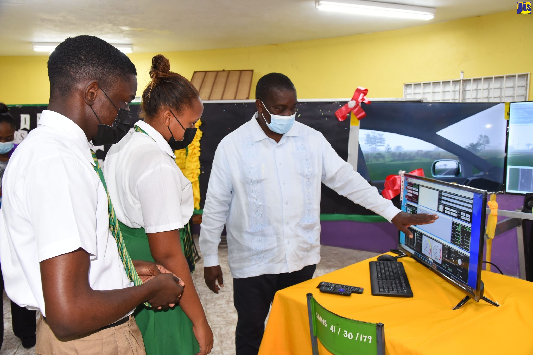 Minister of Transport and Mining, Hon. Robert Montague (right); Head Boy of St. Mary High School, Ajani Campbell (left) and Head Girl, Ashanna Douglas, inspect the driving simulator handed over by the Island Traffic Authority (ITA) to St. Mary High School. The handover ceremony was held on Wednesday (December 15).