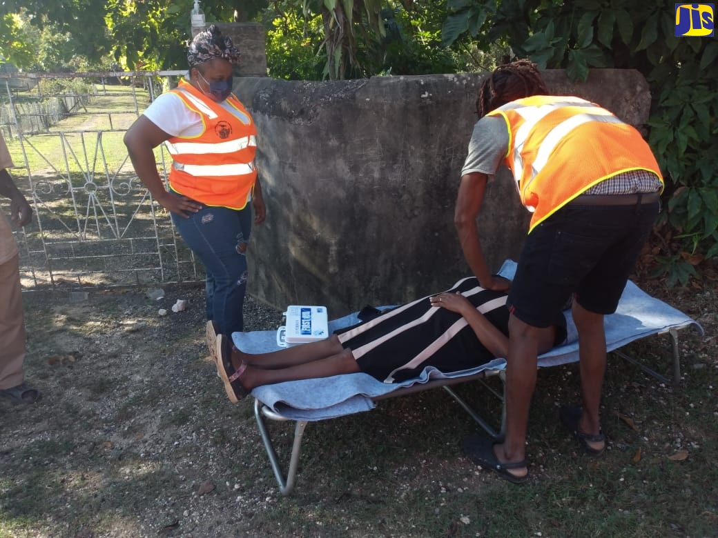 Member of the Community Disaster Risk Management group in New River, St. Elizabeth, Nacar Rose (right), provide emergency aid to a resident during a community earthquake and evacuation drill in the area on Tuesday (January 18).  Looking on is another member of the committee, Kadian Dunkley (left).