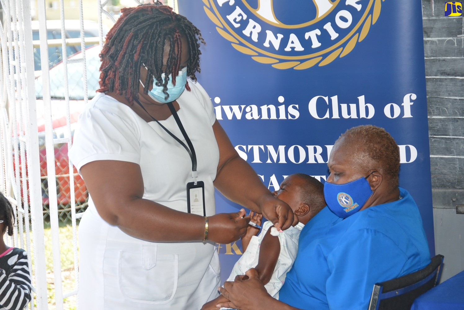 Nurse at the Savanna-la-Mar Health Centre, Shirnette McIntosh, administers a vaccine to a child, while Distinguished President of the Kiwanis Club of Westmoreland Capital, Denise Ennis, provides support, during an immunisation drive at the Hatfield Early Childhood Institution in Westmoreland on Tuesday (January 25).