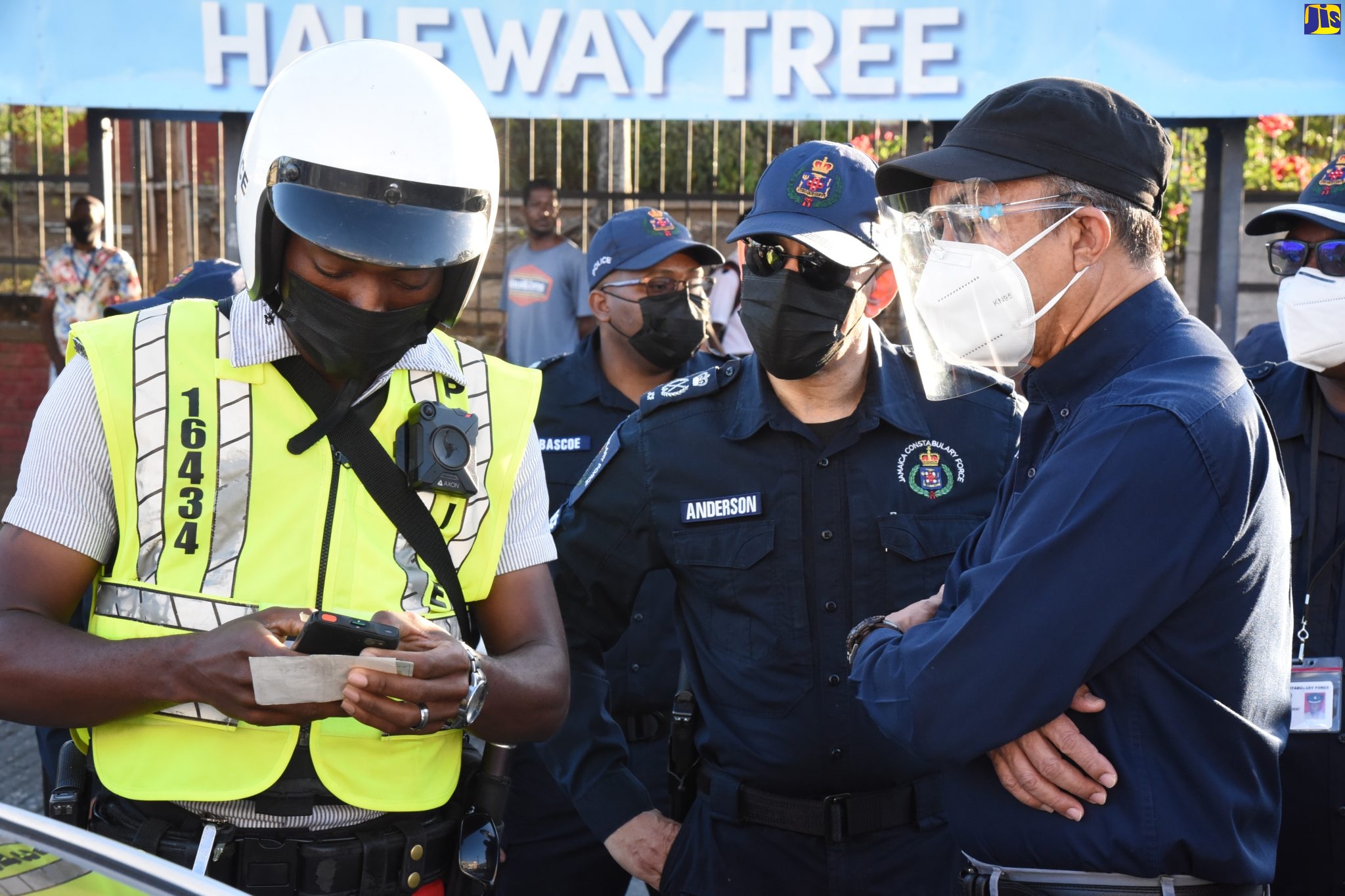 Minister of National Security,  Hon. Dr. Horace Chang (right), and Commissioner of Police, Major General Antony Anderson (centre), observe as Constable Alex Fredankey demonstrates the use of the Jamaica Constabulary Force (JCF) Smart Check E-Ticketing System, during a  tour of Half-Way Tree, Kingston, on Wednesday (January 12) to witness the use of the system in the field.