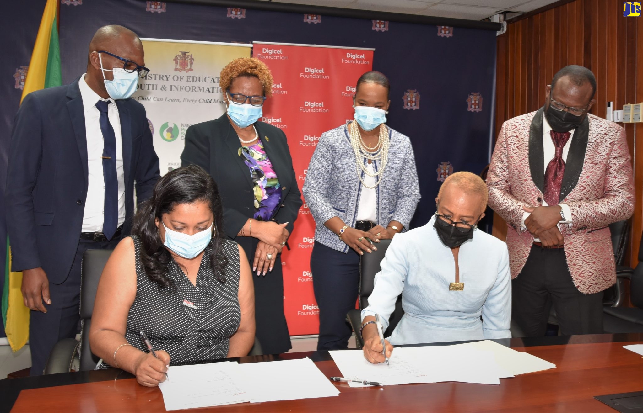 Minister of Education and Youth, Hon. Fayval Williams (seated right) and Chief Executive Officer of the Digicel Foundation, Charmaine Daniels (seated left), sign the agreement for the establishment of a Smart Computer Lab at the Harry Watch Primary School in Manchester. Observing (from left, standing) are Principal of the school, Fitzroy Francis; Acting Permanent Secretary in the Ministry, Maureen Dwyer; Acting Chief Education Officer, Dr. Kasan Troupe; and Regional Director for Region 5, Ottis Brown. The signing ceremony was held at the Ministry in Kingston on Wednesday (February 2).