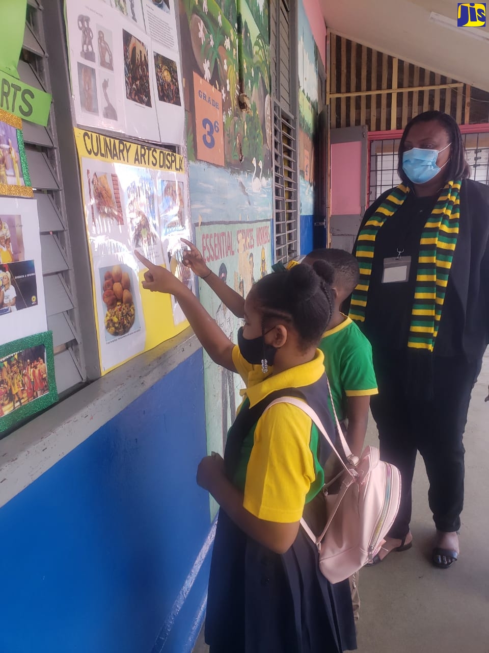 Grade four students of Corinaldi Avenue Primary School in St. James Jhiana Sinclair (left) and Marquin Thorpe (centre) read a culinary-themed display at the school during Jamaica Day on Friday, February 25. Looking on is Acting Principal of the institution, Deon Stern-Anglin.