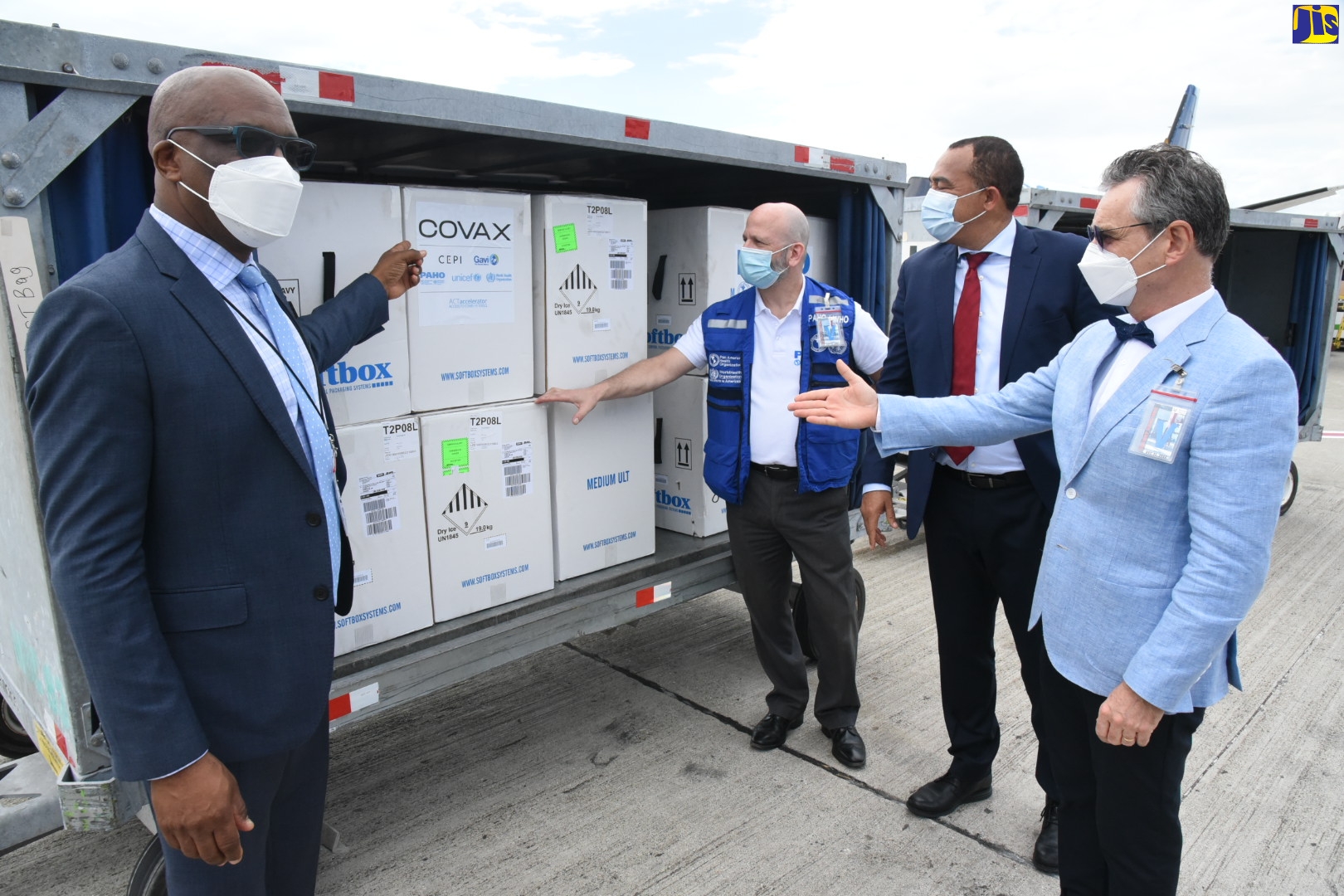Minister of State in the Ministry of Foreign Affairs and Foreign Trade, Senator the Hon. Leslie Campbell (left), points to  batch of vaccines donated by the French Government today, (February 7), after arrival at the Norman Manley International Airport.. Joining him are Minister of Health and Wellness, Dr. the Hon. Christopher Tufton (second right); French Ambassador to Jamaica, His Excellency Olivier Guyonvarch (right) and Pan-American Health Organization Representative in Jamaica, Bermuda and the Cayman Islands, Ian Stein.  