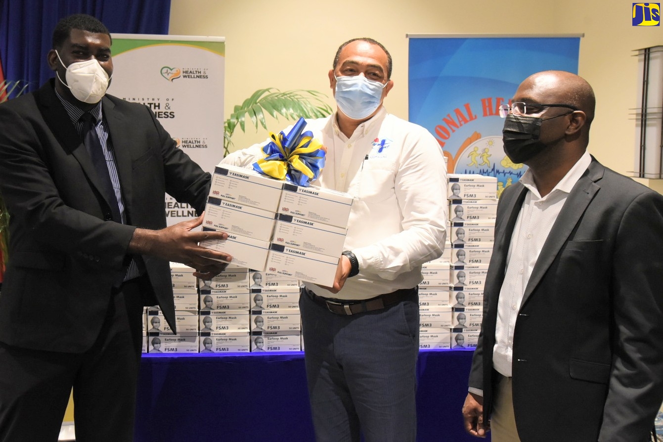 Minister of Health and Wellness, Dr. the Hon. Christopher Tufton (centre), hands over disposable masks to Deputy Commissioner, Department of Correctional Services (DCS), Dr. Marc Thomas. Looking on is Acting Board Chairman, National Health Fund (NHF), Shane Dalling. Occasion was a ceremony for the handover of two million disposable masks to several key entities and vulnerable groups to aid in the prevention and control of the coronavirus (COVID-19), at the Pegasus Hotel in Kingston on Friday (February 11).