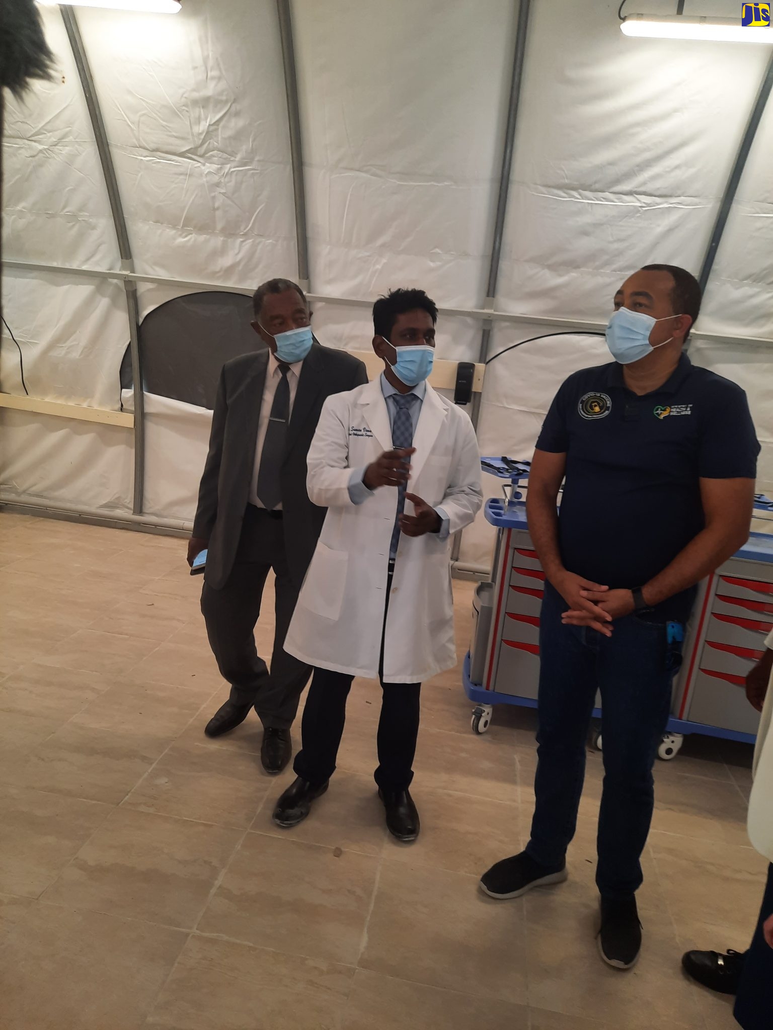 Minister of Health and Wellness, Dr. the Hon. Christopher Tufton (right), listens attentively to Senior Medical Officer at the Savanna-la-Mar Public Hospital in Westmoreland, Dr. Suman Vemu (centre,) during a tour of the new field hospital. Looking on is Mayor of Savanna-la-Mar and Chairman of the Westmoreland Municipal Corporation, Bertel Moore. The facility, located on the grounds of the Savanna-la-Mar Public Hospital, was officially opened on Tuesday (February 2).