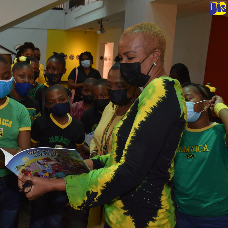 Minister of Education and Youth, Hon. Fayval Williams (right), and Minister of Culture, Gender, Entertainment and Sport, Hon Olivia Grange (second right), look through a Jamaican colouring book with primary-school students, during a visit to the National Gallery of Jamaica, downtown Kingston, on Jamaica Day (February 25).