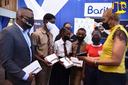 Minister of Education and Youth, Hon. Fayval Williams (right), demonstrates the capabilities of a tablet to students during a ceremony for the presentation of 310 tablets and 15 laptops by the Barita Foundation under the ‘One Laptop or Tablet Per Child’ initiative. The handing-over took place on March 10 at the Tivoli Gardens High School in Kington. The students (from second left) are: Omary Edwards and Natasha Quavers of Tivoli Gardens High; and Kanye Ferguson and Kayla Lawman of Lawrence Tavern Primary in St. Andrew. Also looking on are Managing Director of Barita Unit Trust, Jason Chambers (left); and Executive Director, Barita Foundation, Tanketa Chance -Wilson (in background).