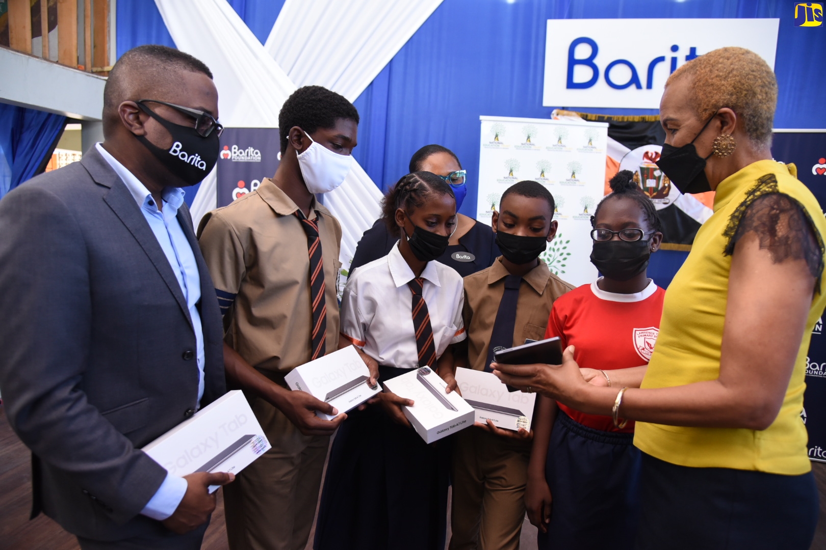 Minister of Education and Youth, Hon. Fayval Williams (right), demonstrates the capabilities of a tablet to students during a ceremony for the presentation of 310 tablets and 15 laptops by the Barita Foundation under the ‘One Laptop or Tablet Per Child’ initiative. The handing-over took place on March 10 at the Tivoli Gardens High School in Kington. The students (from second left) are: Omary Edwards and Natasha Quavers of Tivoli Gardens High; and Kanye Ferguson and Kayla Lawman of Lawrence Tavern Primary in St. Andrew. Also looking on are Managing Director of Barita Unit Trust, Jason Chambers (left); and Executive Director, Barita Foundation, Tanketa Chance -Wilson (in background).
