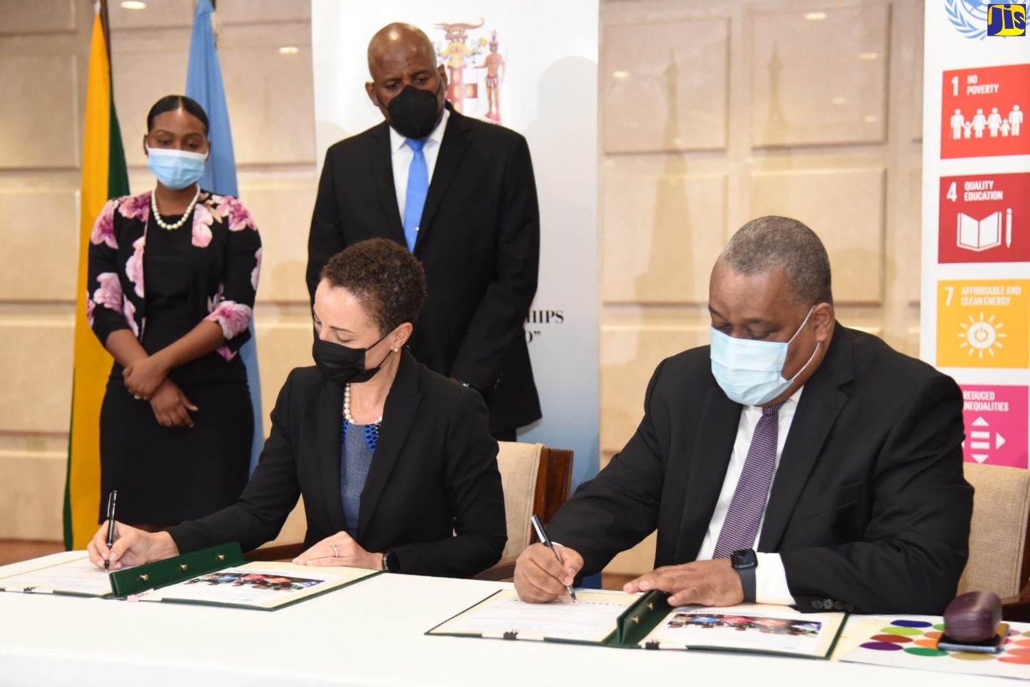 Minister of Foreign Affairs and Foreign Trade, Senator the Hon. Kamina Johnson Smith (seated left) and United Nations Resident Coordinator, Dr. Garry Conille (seated right), sign the 2022/26 Multi-Country Sustainable Development Convention Framework (MSDCF) during the signing ceremony held at the Ministry in Kingston yesterday (March 15). The signing was witnessed by Director-General of the Planning Institute of Jamaica (PIOJ) Dr. Wayne Henry (standing right), while Foreign Service Officer from the Ministry