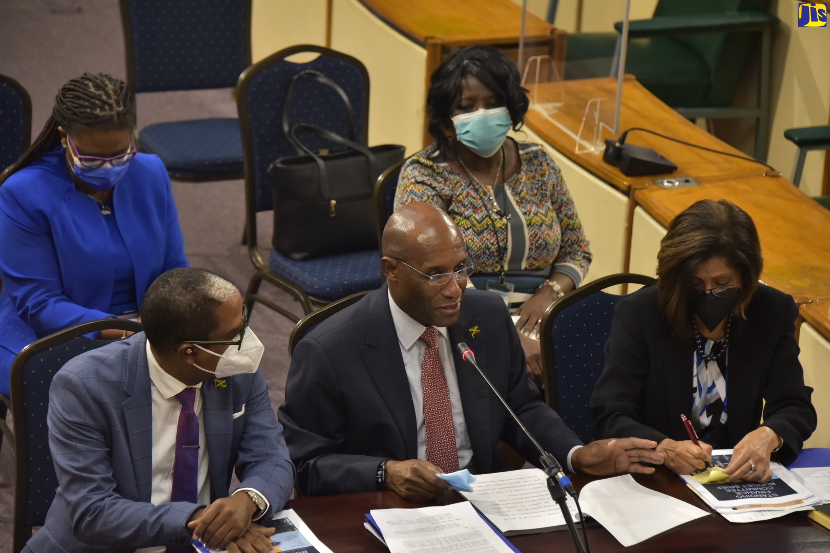 Minister of Industry, Investment and Commerce, Senator the Hon. Aubyn Hill (centre), responds to questions during Thursday’s (March 3) meeting of the Standing Finance Committee of the House of Representatives, at Gordon House. Among those accompanying him are State Minister in the Ministry, Dr. the Hon. Norman Dunn (left, front row), and Permanent Secretary, Sancia Bennett Templer (right, front row).
