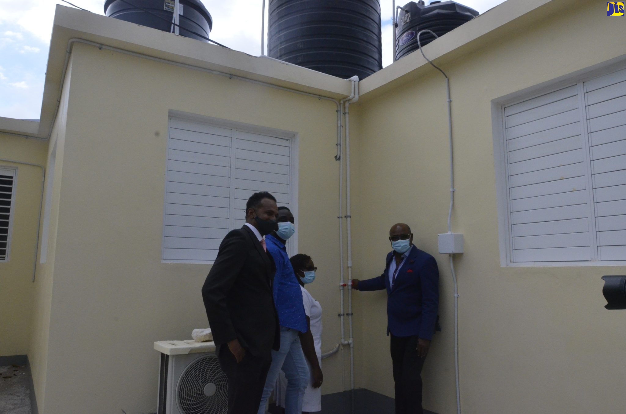 Tourism Minister, Hon. Edmund Bartlett (right), is joined by Executive Director of the Tourism Enhancement Fund (TEF), Dr. Carey Wallace (left); Councillor for the Rose Hall Division, Anthony Murray; and Registered Midwife of the Barrett Town Health Centre, Noreen Roper, in commissioning into service, two 650-gallon water storage tanks, at the Barrett Town Health Centre in St. James on Friday (March 11).