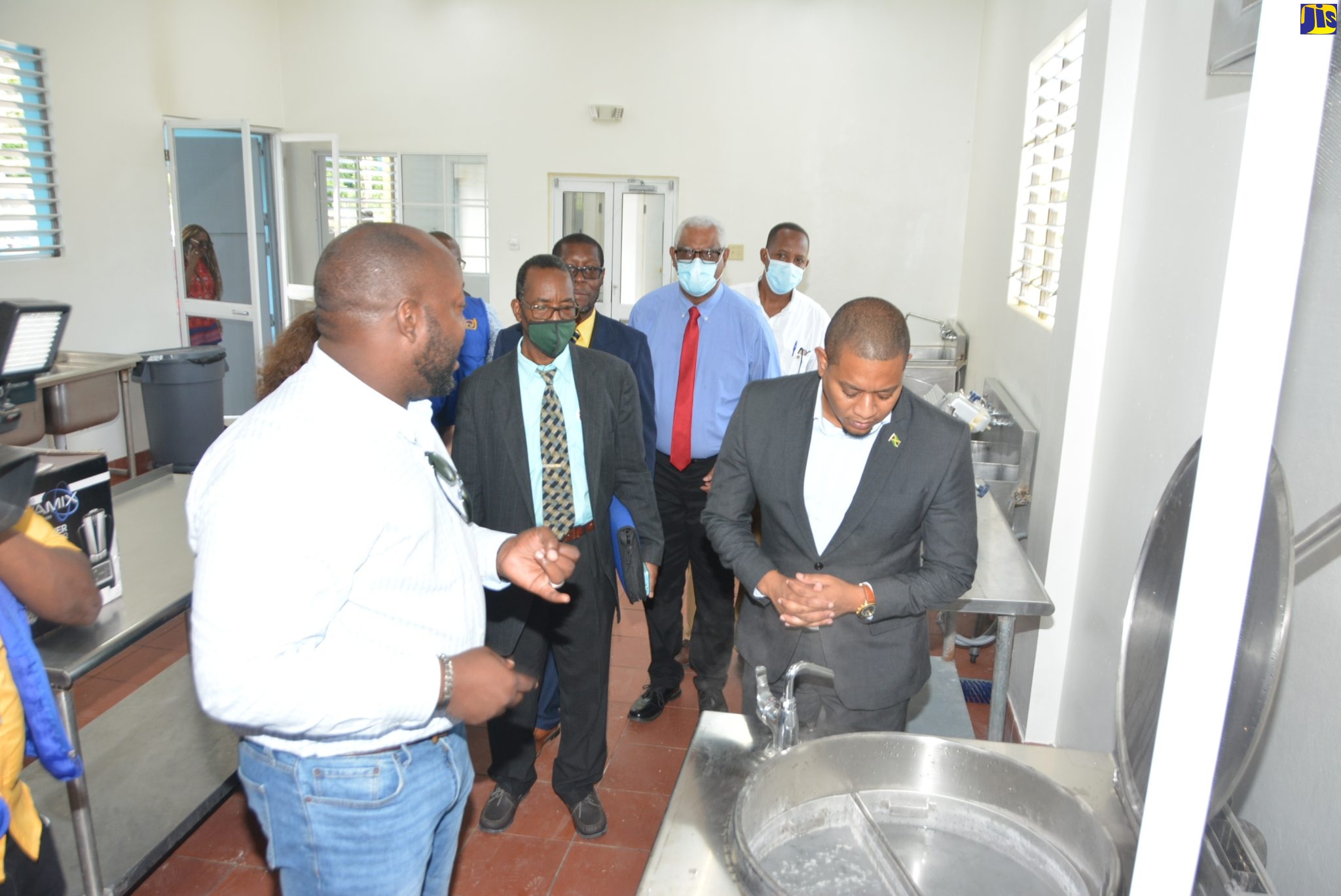 Minister without Portfolio in the Office of the Prime Minister, Hon. Floyd Green (right), examines a piece of equipment  as Project Manager of J. Wray & Nephew Limited, Dwight Mullings (left), conducts  a tour of the $47-million Elim Agro-Processing Plant that was officially handed over  to Sydney Pagon STEM Academy in St Elizabeth and the wider farming community, on Thursday (March 24). 