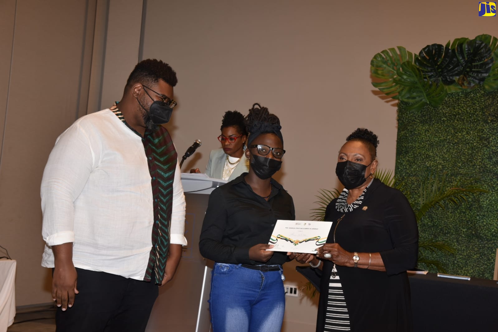 Culture, Gender, Entertainment and Sport Minister, Hon. Olivia Grange (right), presents Edna Manley student Kiana Jackson with her certificate. The event was the Jamaica Creative Internship awards ceremony held on Wednesday (March 9) at the AC Marriott Hotel in Kingston. A total of 60 internships are to be awarded through the programme for this year.
Also pictured is Director, Events Management and Production, Jamaica Cultural Development Commission (JCDC), Gregory Simms (left), and National Director of the Entertainment, Culture and Creative Industries Council (Jamaica Creative), Marisa Benain (background).   
