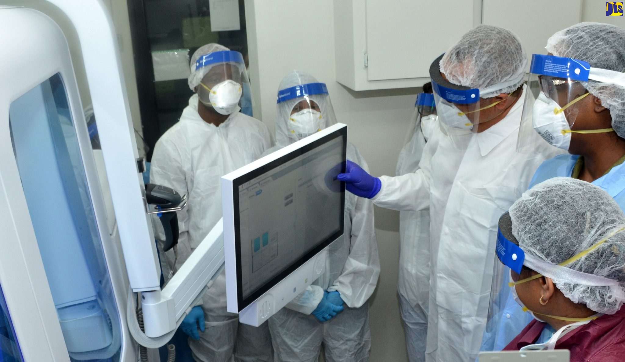 Minister of Health and Wellness, Dr. the Hon. Christopher Tufton (fourth left), looks at information on the screen of the Cobas machine, which was commissioned into service at the National Public Health Laboratory in Kingston, in April 2020. Observing are Chief Medical Officer, Jacquiline Bisasor McKenzie (right); Director of the National Laboratory Services, Dr. Michelle Hamilton (second right), and other staff members at the facility.