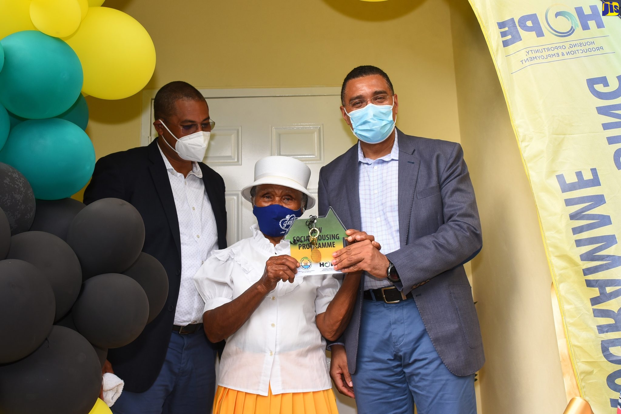 Prime Minister, the Most Hon. Andrew Holness (left), hands over the keys to a new one-bedroom house, built under the New Social Housing Programme (NSHP), to beneficiary Mary Gentles, during a ceremony held in Mike Town, North Western Manchester on Friday (March 11).  Sharing the moment is Member of Parliament for the area, Mikael Phillips.
