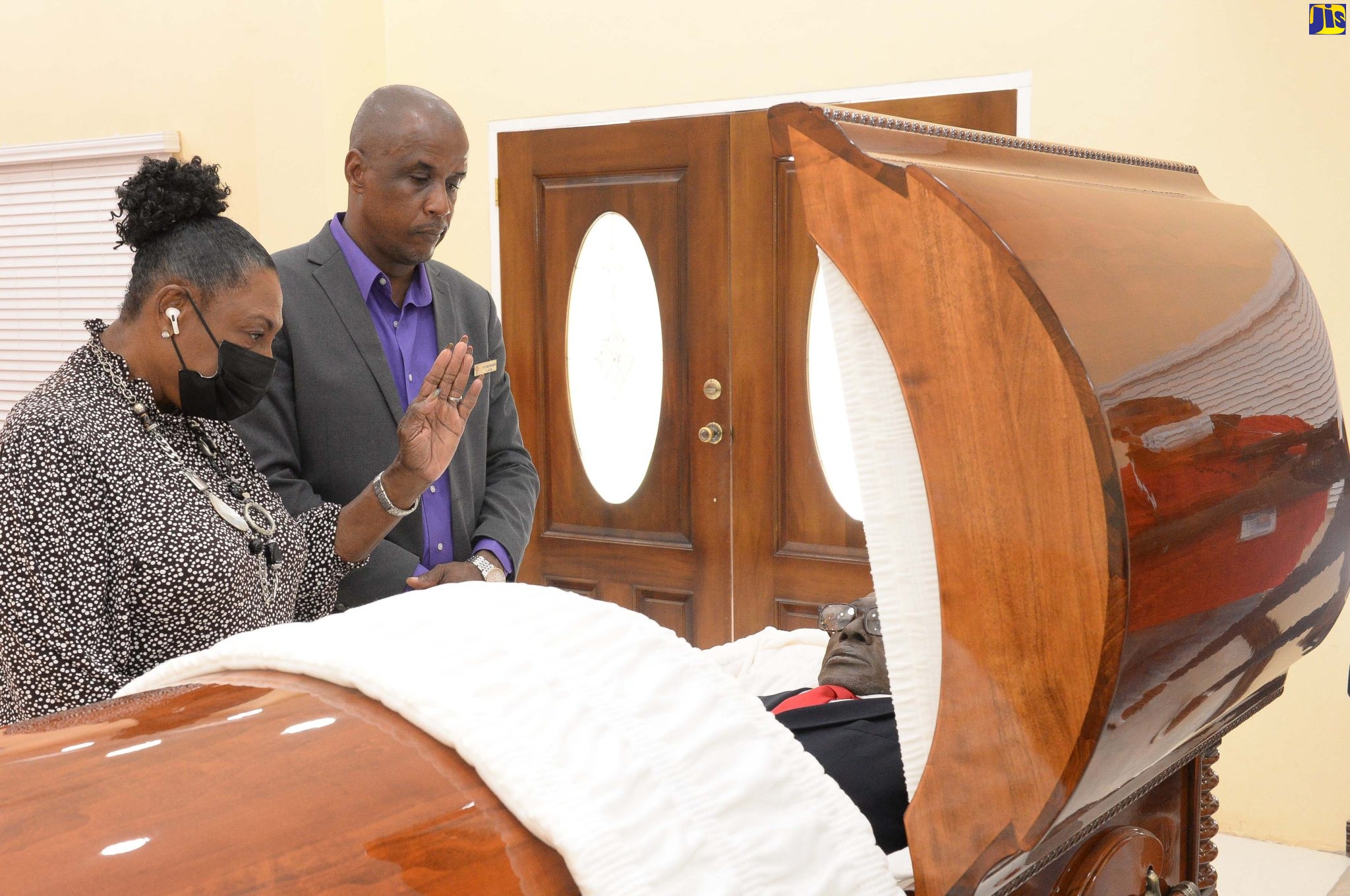 Minister of Culture, Gender, Entertainment and Sport, Hon. Olivia Grange, views the body of late veteran journalist, Winston Witter, at Perry’s Funeral Home in Spanish Town, St. Catherine, on Saturday (March 5). With her is the establishment’s Chief Executive Officer, Peter Perry.

