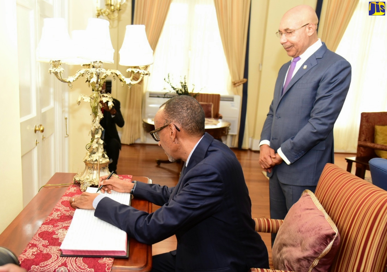 Governor - General His Excellency the Most Hon. Sir Patrick Allen (right) observes as President of the Republic of Rwanda, his Excellency Paul Kagame signs the guest book during a courtesy call on April 14 at King's House. President Kagame is conducting a three day State visit from April 13 to 15 as part of efforts to deepen bilateral relations between the two countries.