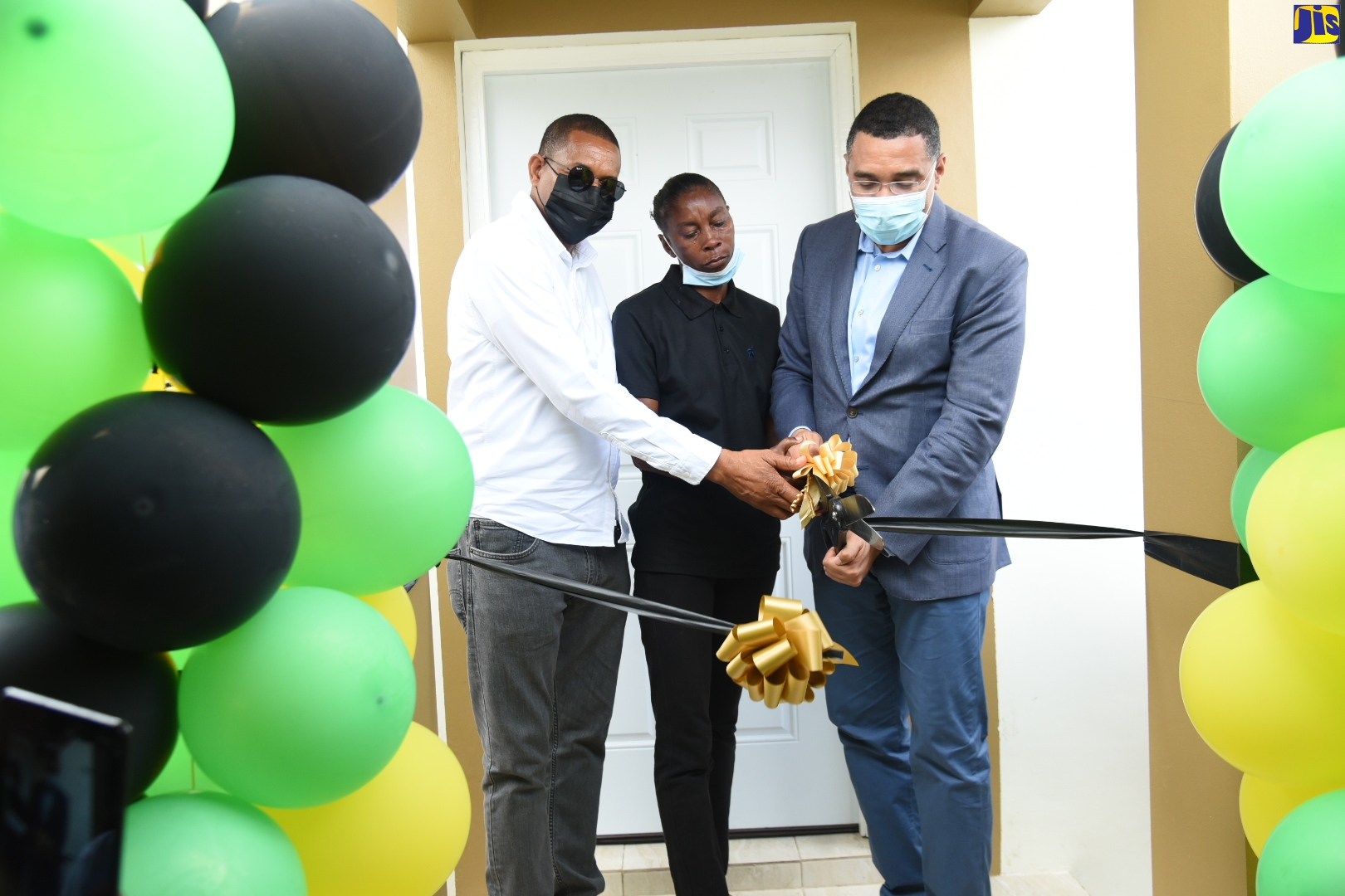 Prime Minister, the Most Hon. Andrew Holness (right), and Member of Parliament for Hanover Eastern, Dave Hume Brown (left), join New Social Housing Programme (NSHP) beneficiary, Michelle Campbell (centre), in cutting the ribbon to her new three-bedroom housing unit in Bessie Baker, Mount Peto, Hanover on Thursday, April 7.  
 
